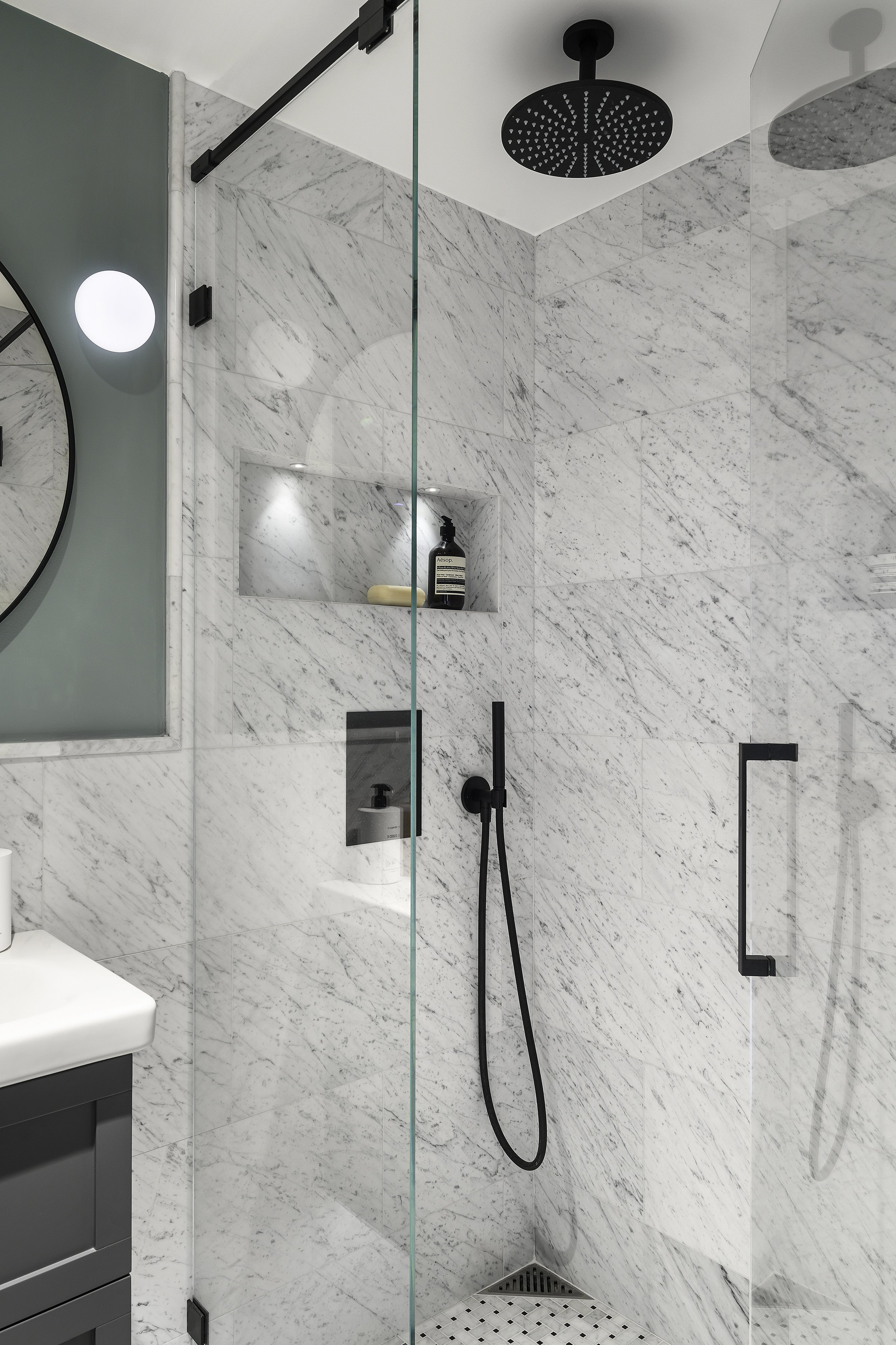 Carraramarmor och svarta detaljer i duschhörna.