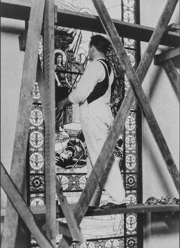 PAINTING THE WINDOWS. Fausto Tasca painted the faces and all other details onto the stained–glass windows. This publicity photo, taken by a local newspaper photographer, shows Tasca at work on the windows.