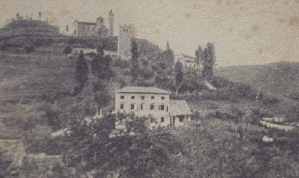 SAN ZENONE DEGLI EZZELINI. San Zenone is a quiet village in the northern Italian province of Treviso. This photograph of the hills surrounding San Zenone was taken in the early 1900's. It shows the vista one would see from near the Tasca family home. Fausto Tasca was an accomplished photographer, so it is very possible that he took this photograph before his departure from San Zenone. The photo shows the hill which dominates the countryside, and its well–known chapel called "Madonna del Monte." The square "Tower of the Ezzelini" can be seen slightly below the church and to its right.