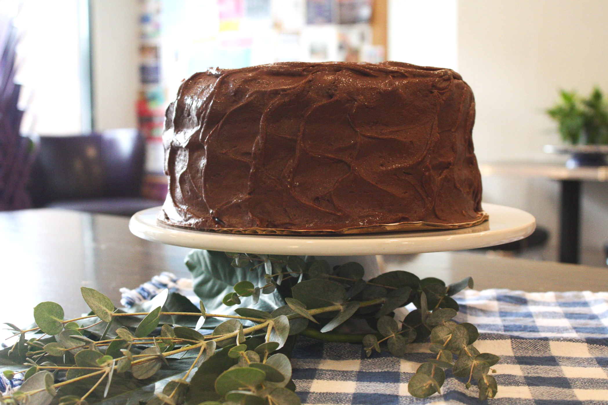 Round chocolate cake with chocolate icing on round cake stand.