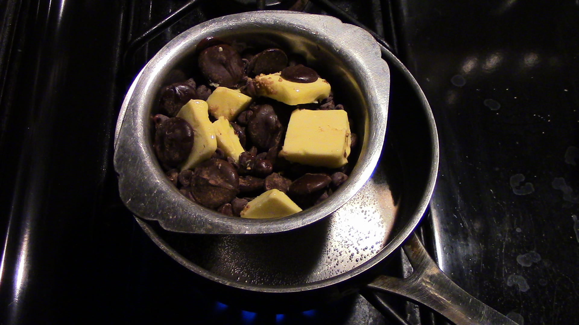 Gently melting the butter and chocolate in a hot water bath — home-rigged double boiler (aka baine marie). Gentle means the heat of the water isn't touching the vessel that the butter and chocolate are in. Also keep water out of the vessel or textural issues ensue.