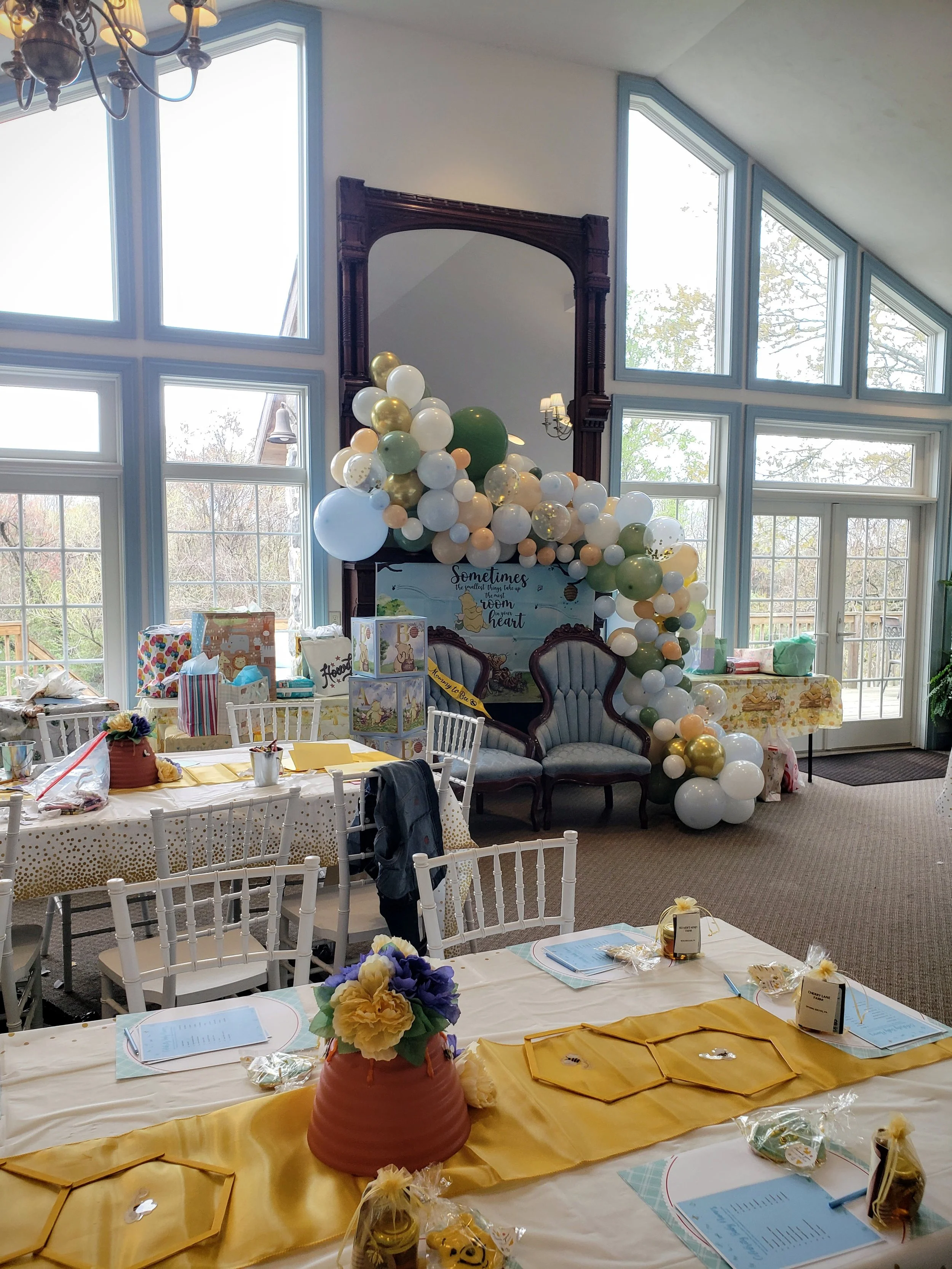 Winnie the Pooh / Honey-themed baby shower in the Solarium event venue - photo features balloons, gifts, and beehive centerpieces