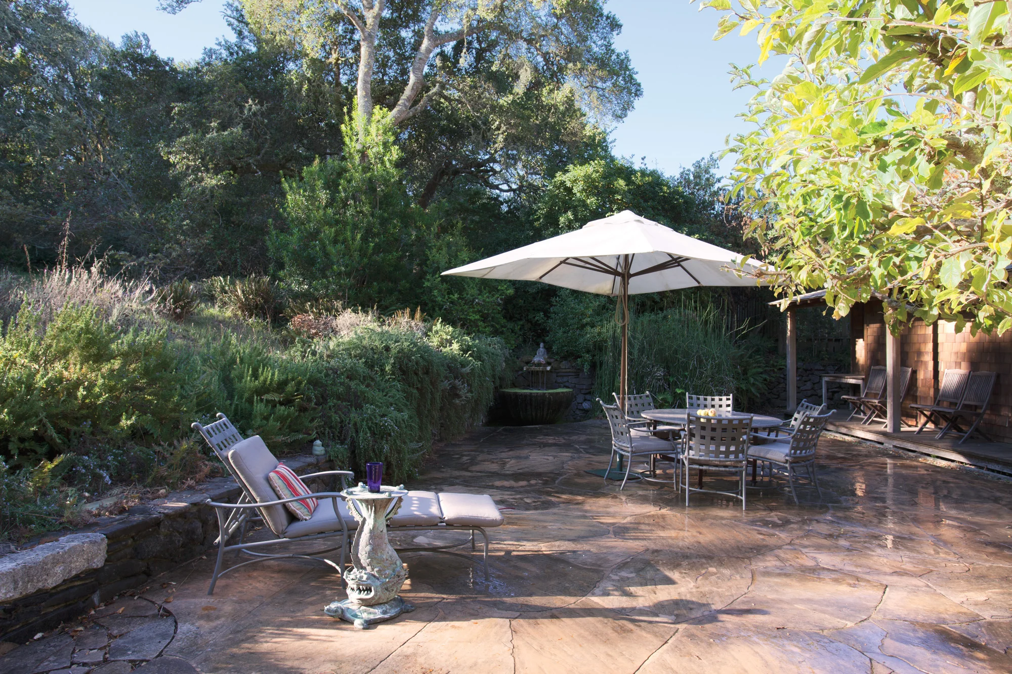 Adjacent the sliding glass doors of the kitchen/den/dining area/tv corner and hemmed in by apple trees and rosemary is an expansive terrace with water elements and outdoor furniture and a BBQ.