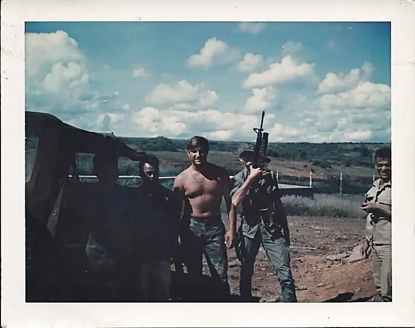 On the back of the photo it reads: 1305 hrs, Thu 23 July '70 V.C. Prisoner Of War Camp, East of Pleiku A.F.B. (my real dad is the one holding a gun) On far right, a POW interpreter, on my left, AIC Tarloton, a guard for POWs. On his left, two V.C. who was captured up on Monkey Mountain which is not shown in this photo. Mirl Hobbs