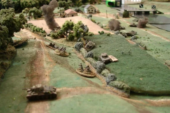 Battle rages About half the M4s are hit, smoking or abandoned at this stage, but are still getting past the lead StuGs. The T34 in the foreground is abandoned after losing its main gun and suffering an engine hit.