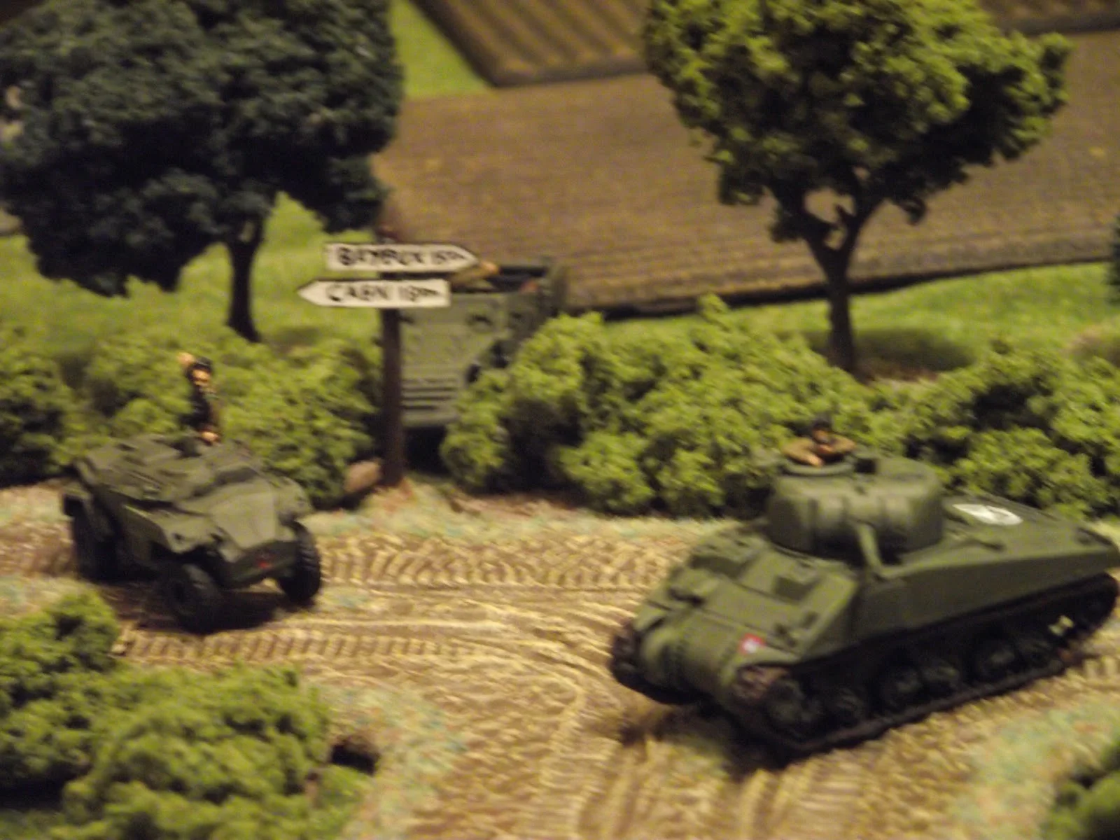 The British cannot seem to spot into the town, so the armour decides to force the issue by advancing around the bend.