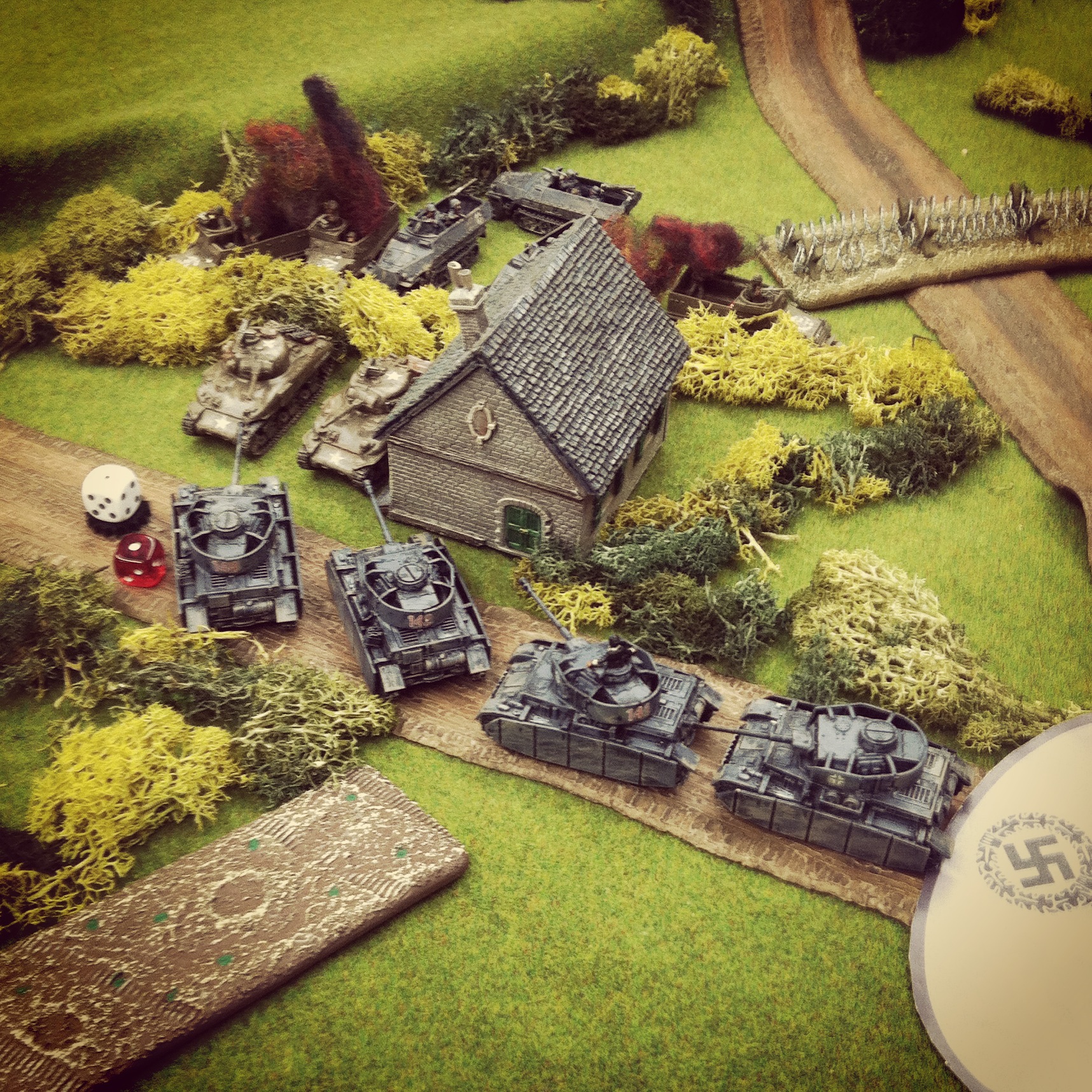 The German Panzer IV column exposes two Shermans behind a farmhouse