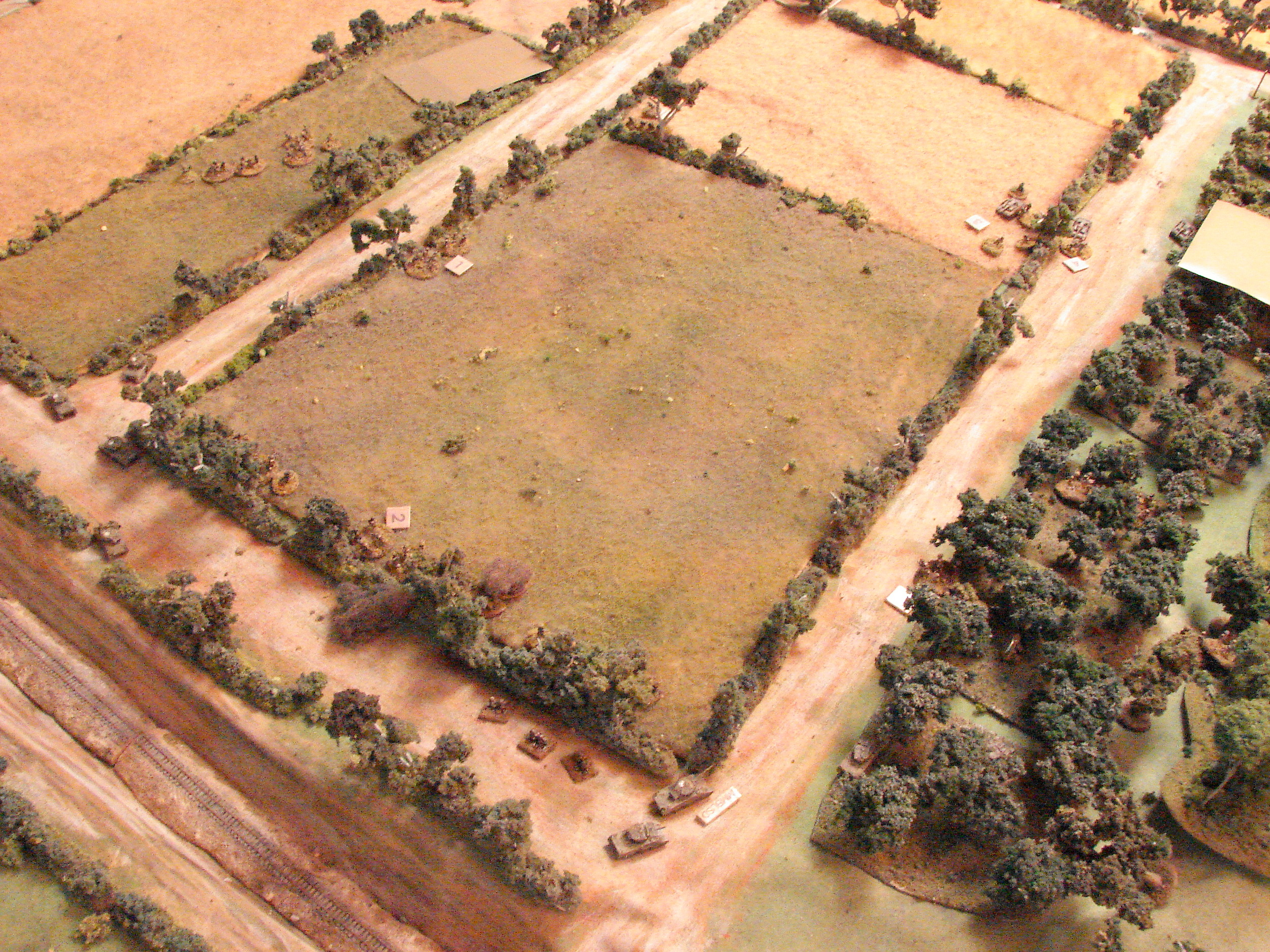 Action down the road One of the Shermans pulled back behind the Firefly after taking a hit. Meanwhile the two Shermans in the orchard are firing at the StuGs which are firing down the road at the Firefly. Infantry in the orchard is trading shots with grenadiers across the road in the hedge.