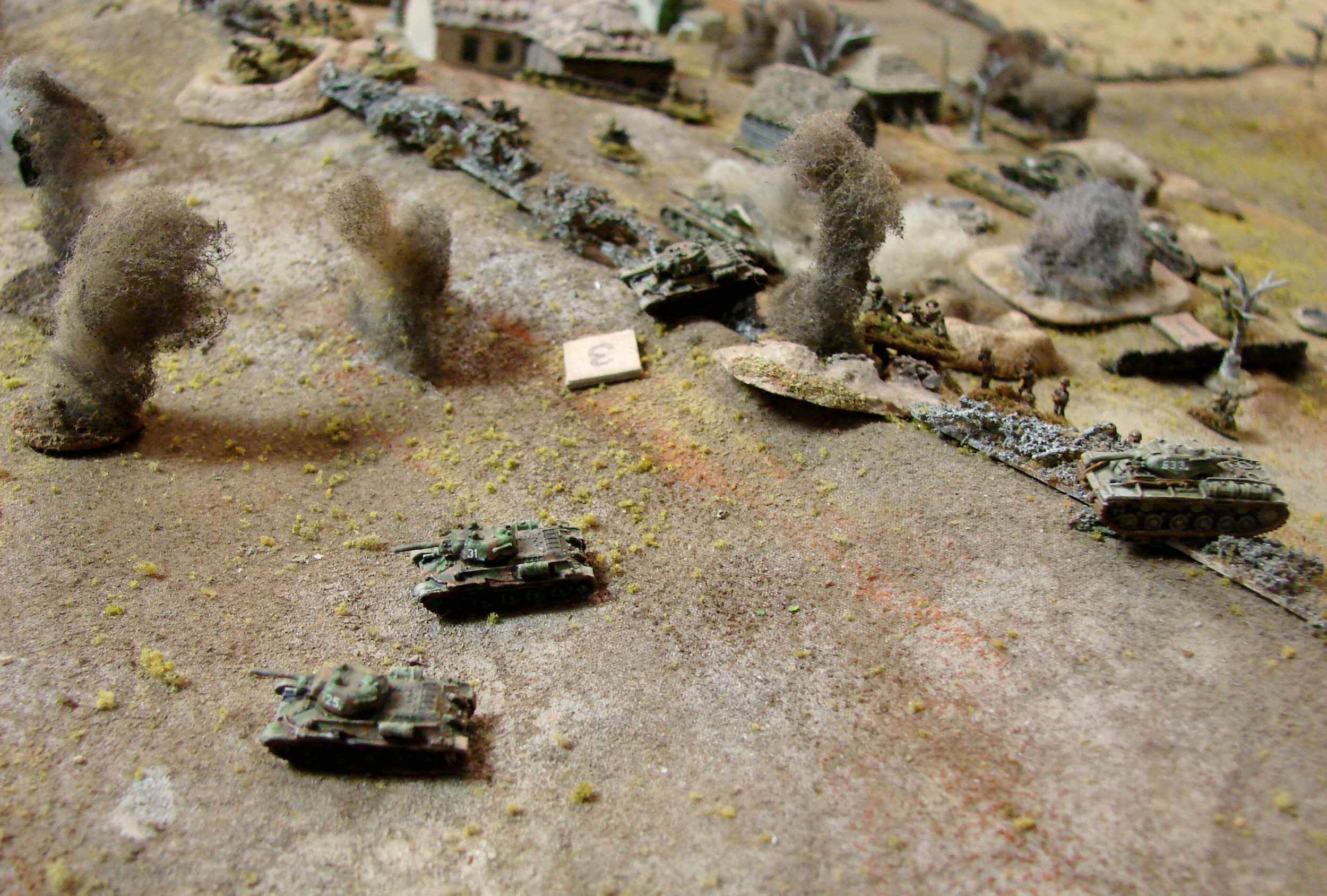 T-34s try to run around the left Three of the T-34s and the the surviving KV-1s aim to get to the outside of the village and the flank of any German armor coming up. German mortars land between their infantry and the wind break. You can finally see the brown & green camo on my T-34s in this picture.