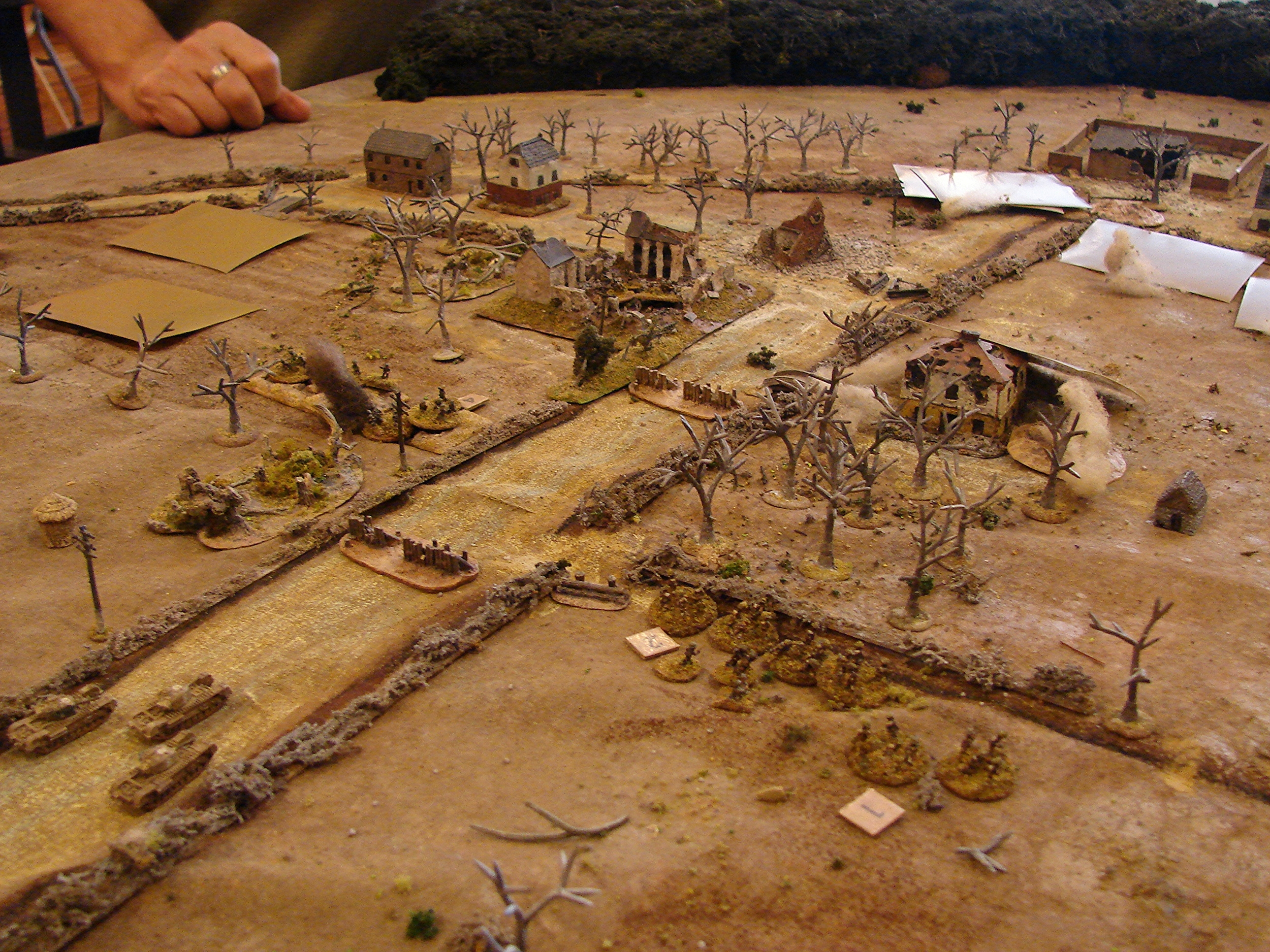 Action in the centre At this point, only one troop of tanks, and one platoon of Brian's has shown up on the board. He has come under fire from a platoon of grenadiers. But he has noticed that there are quite a few other blinds on the table (and probably many more hidden). His other two platoons and a troop of Churchills were suppose to be moving out of the woods to his right. But, alas, they seemed to have gotten lost - or at least had some really crappy die rolls.
