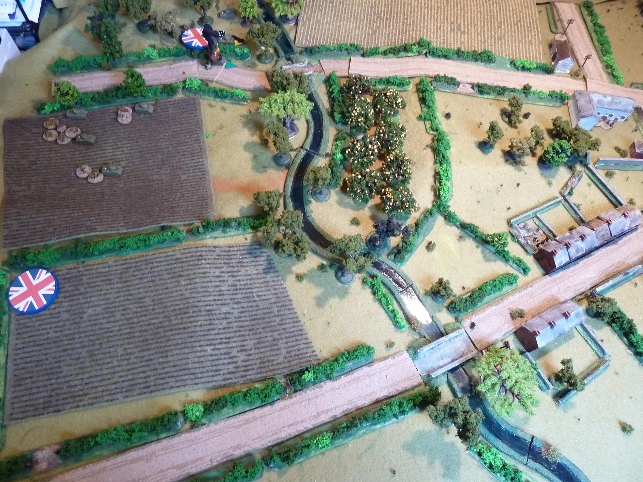 First blood to the Panther, just off cam on the right: a smoking M4. The Canadian second force heads across the ploughed field aiming to cross the river and find cover in the orchard. Quickly spotted by a German sniper tied to an apple tree. Crossing the ploughed field is slow going and the sniper further slows the Canadians with plenty of shock and pins. The Canadian FOO and Vickers head for the high ground on the left.