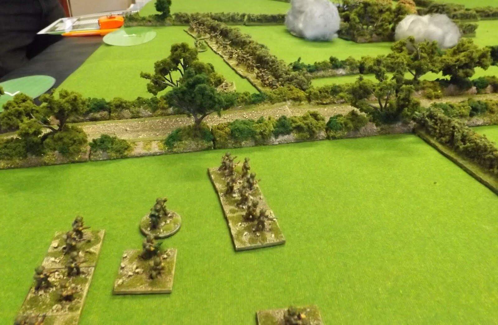 Troops lining hedgerows provide a fire base for those crossing fields trying to find the flank