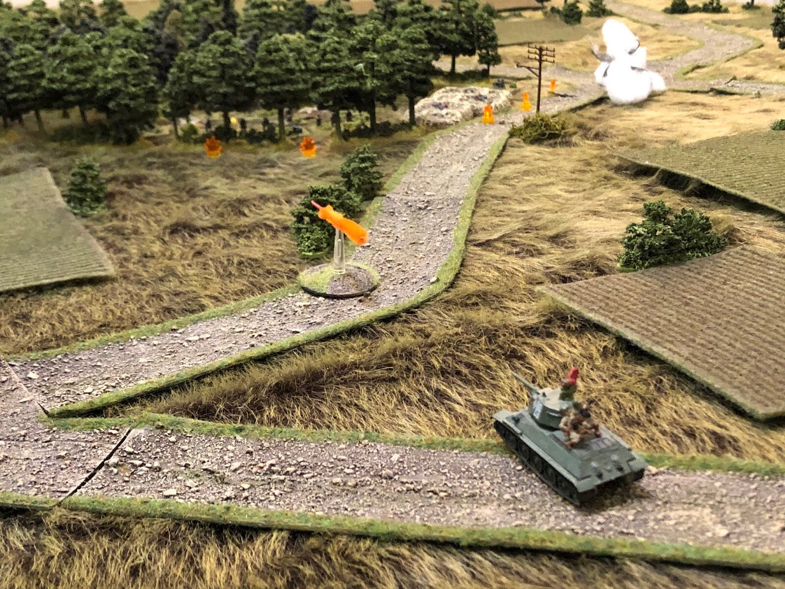  The Communist tank lurches to a halt and fires, launching a 76mm HE round into the wood, but it fails to find flesh.  *This tank moved up and fired on the wood because it failed to spot the German armor, which is off camera to top left. 