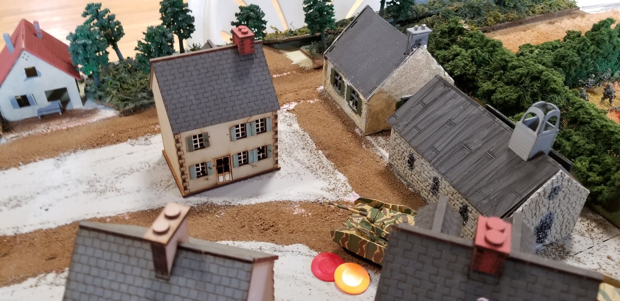 A Panzer IV takes shock and loses an activation from a PIAT in the center building.
