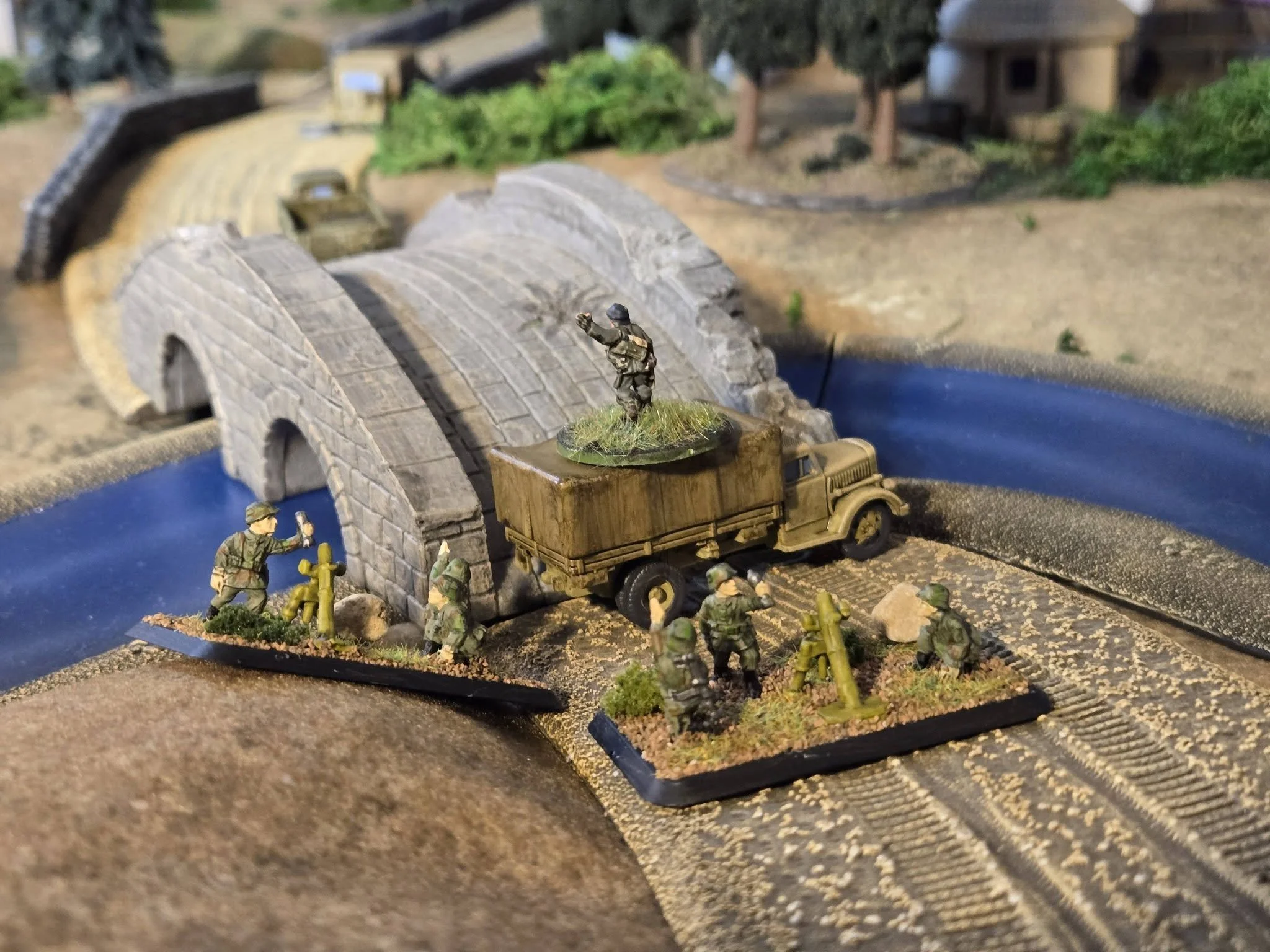 A plucky German leutnant climbs atop an Opel to direct the fire of his mortar teams over the bridge and at the church