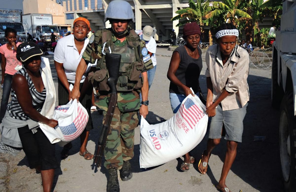 A United Nations peacekeeper helps locals move American food aid in the aftermath of the 2010 earthquake in Haiti. Creative Commons / U.S. Navy