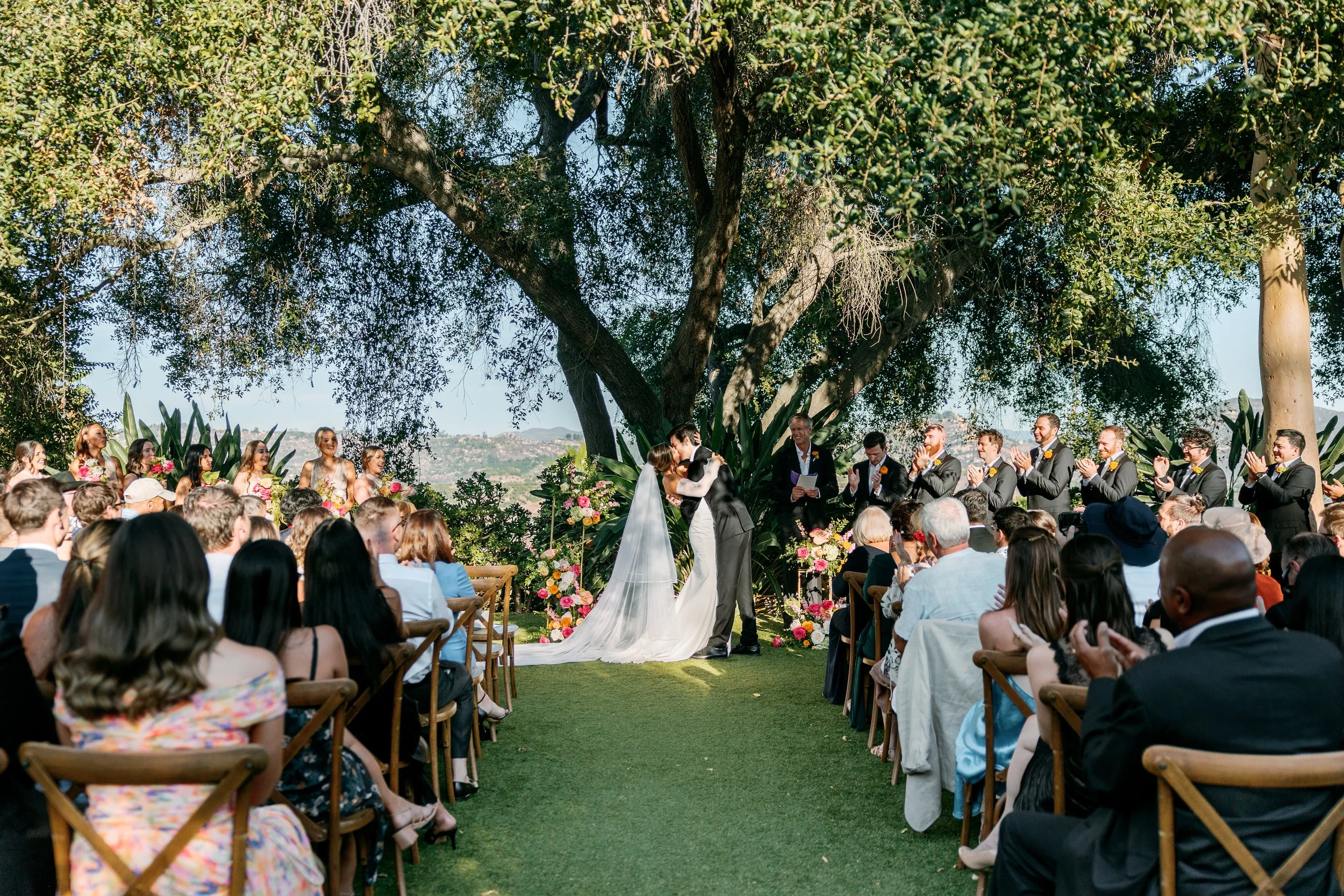 Bride and groom sharing their first kiss during the wedding ceremony at Tivoli Italian Villa in Escondido, California