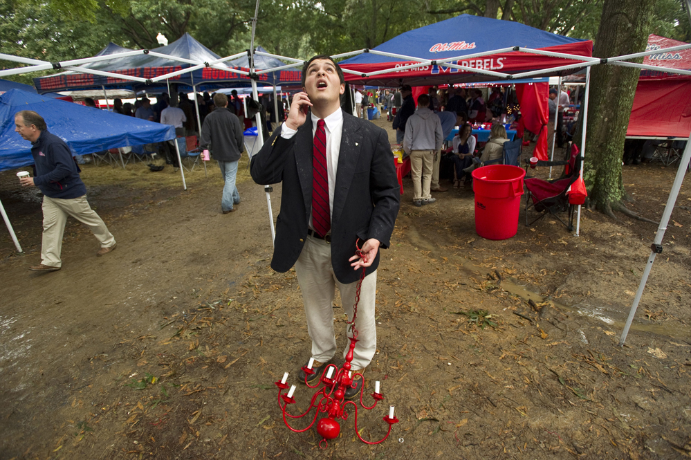 Nate Blumberg calls a friend to ask for advice on how to hang a chandelier from his tent's frame during tailgating at The Grove on the University of Mississippi campus before the Ole Miss Rebels football team takes on Texas A&M University.