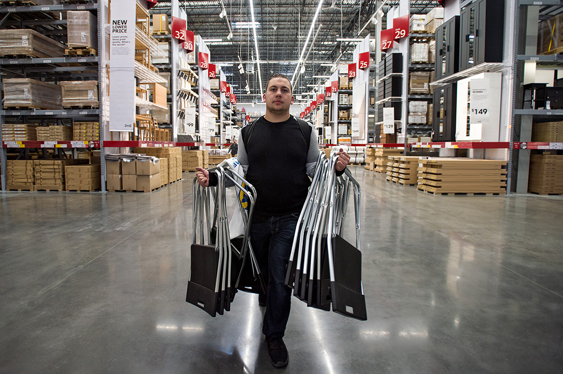Jaylen Roach carries armfuls of stacking chairs as one of the first shoppers inside home furnishing retailer IKEA's new Memphis store during an event marking its grand opening.