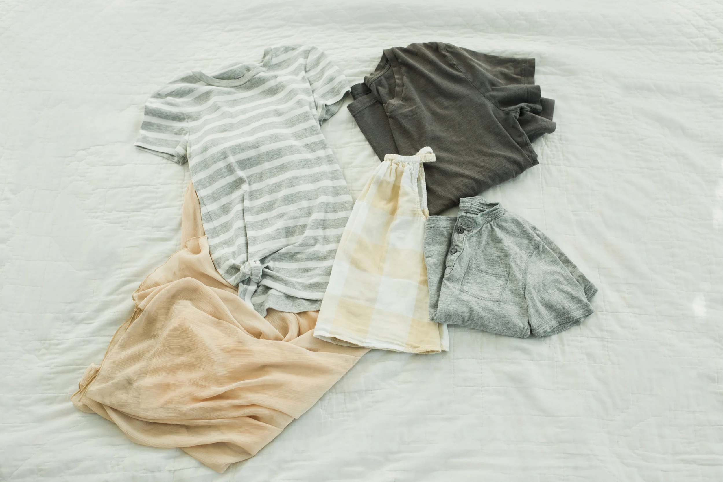 Knotted striped tee with a flowy blush skirt for mom. Gingham dress for girl. Grey henley for boy. Grey v-neck for dad. Since everything is so neutral and working well, I would put dad and boy in khakis.