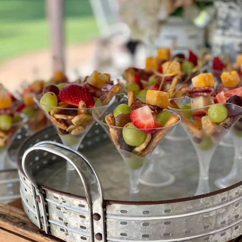 Assorted fruit parfaits in martini glasses on a round metal tray