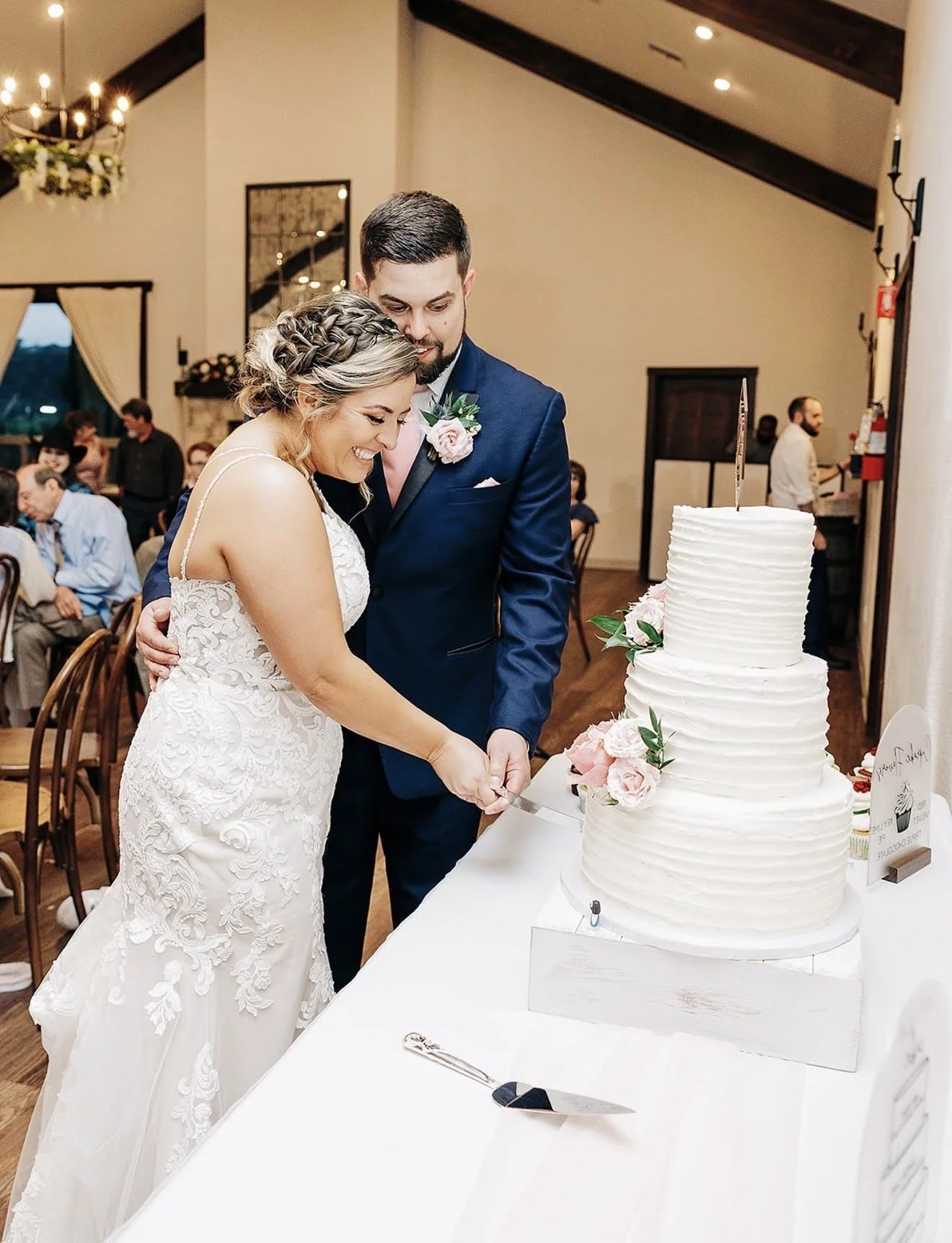 Bride and groom cutting their wedding cake in a reception hall.