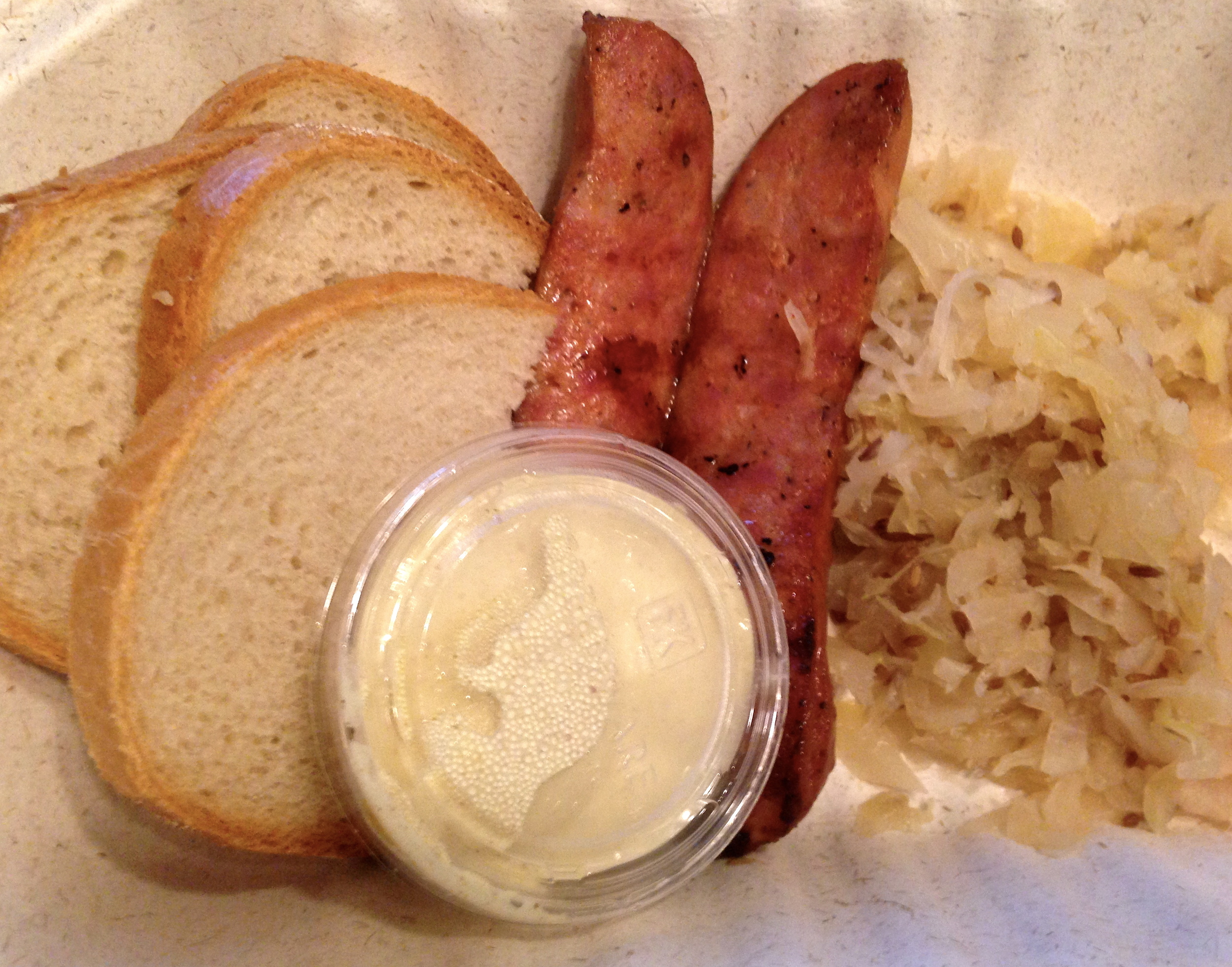Grilled kielbasy, served with sauerkraut, mustard sauce, and slices of fresh bread.