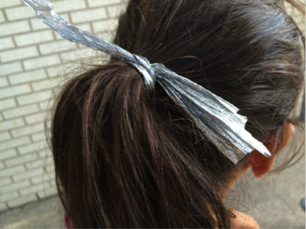 Nine-year old Carla from San Pedro Sula, Honduras used strips from Mylar foil blankets provided at the Border Patrol detention facilities to tie back her tangled hair after 6 days with no shower. McAllen, Texas. Photo credit: Heide Castañeda.