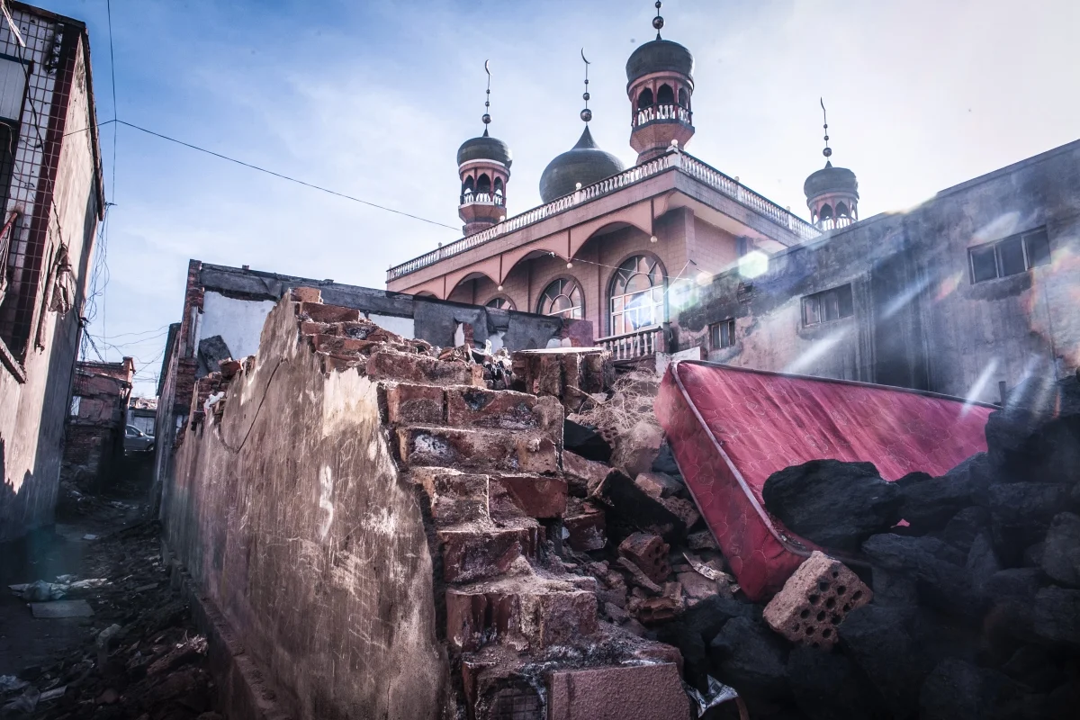 The rubble of Uyghur migrant housing surrounds a neighborhood mosque.
