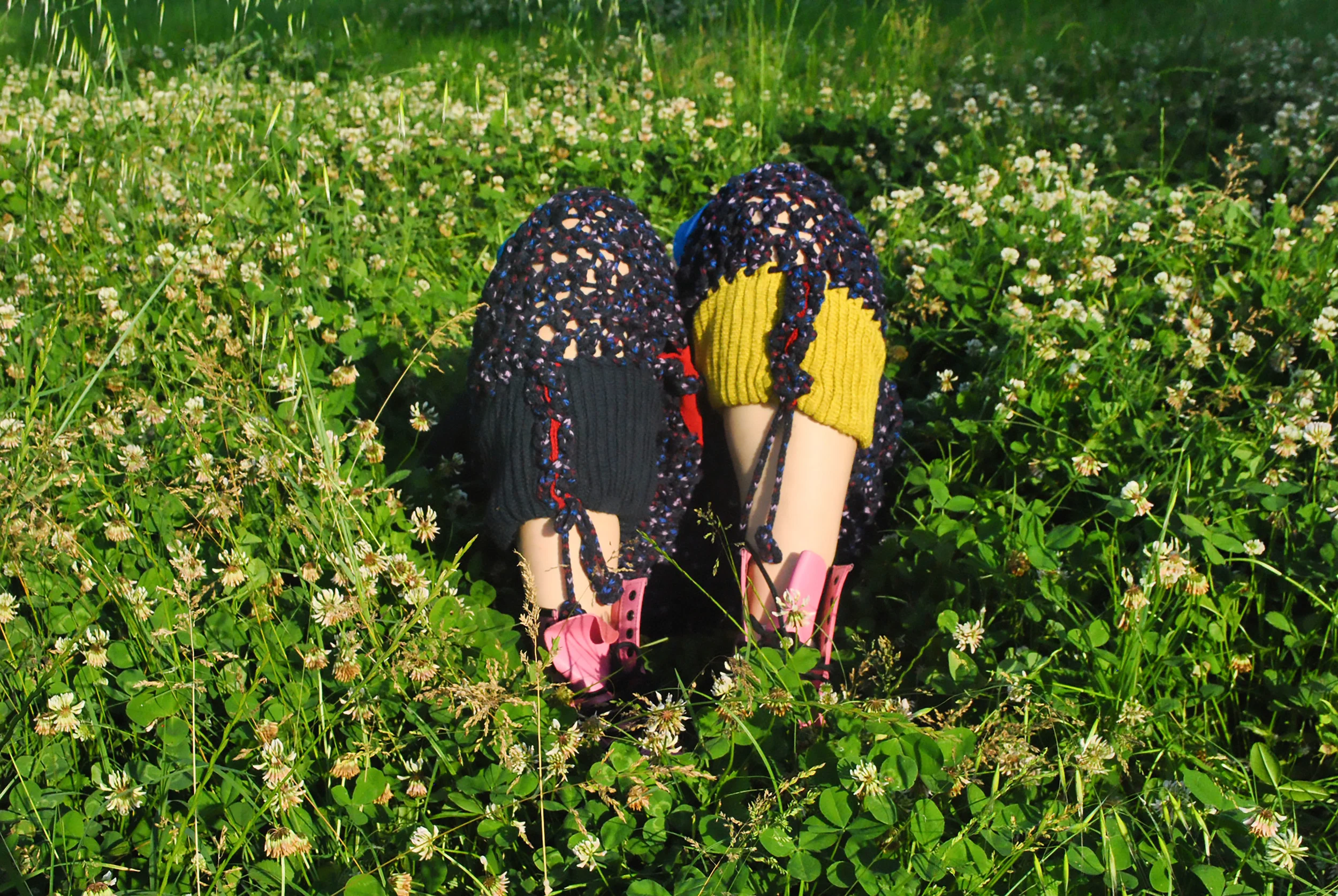 Close-up view of children's shoes and legs in a bed of green clover and small white flowers.