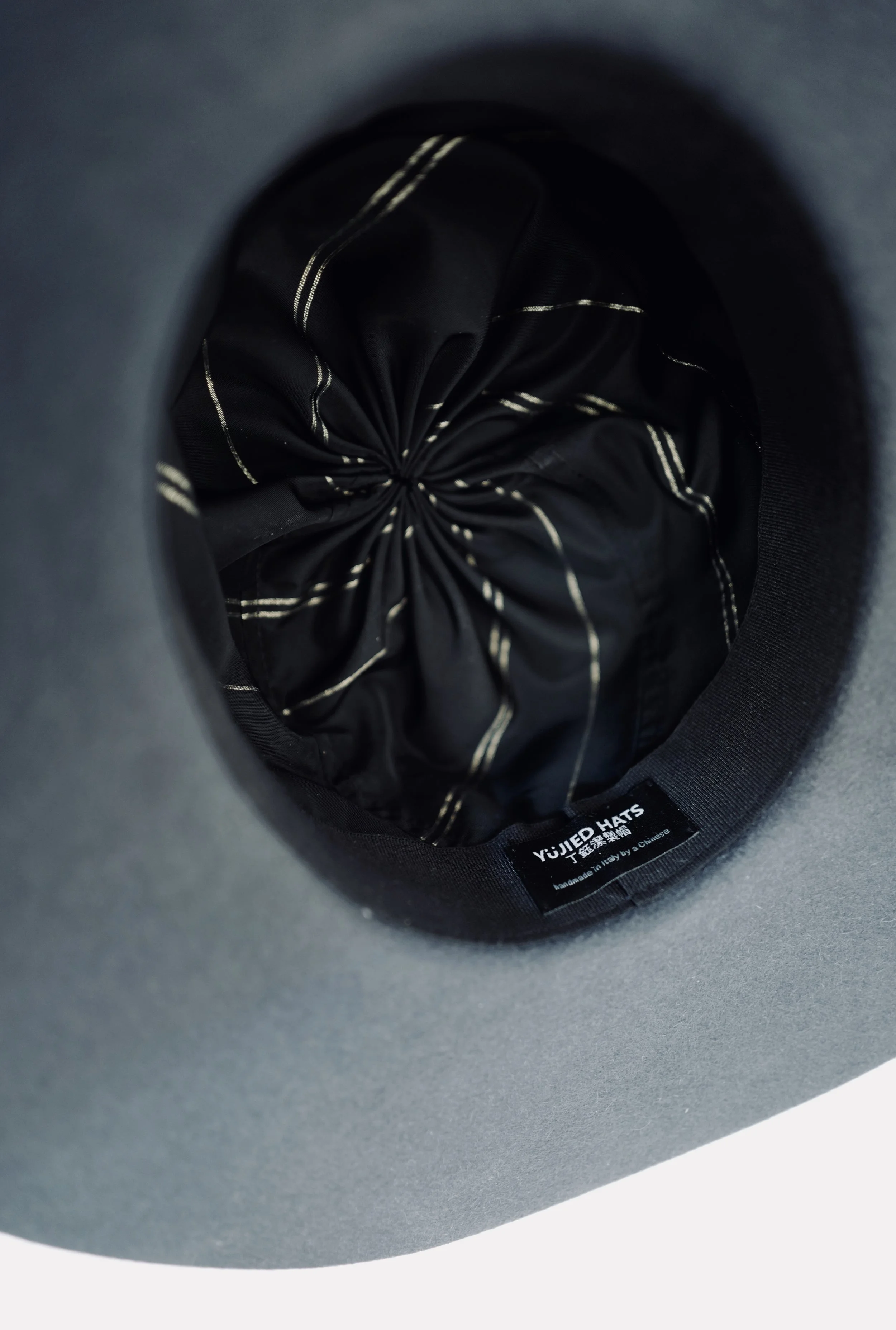 A beige woven sun hat with a white ribbon band displayed on a brown wooden stand.