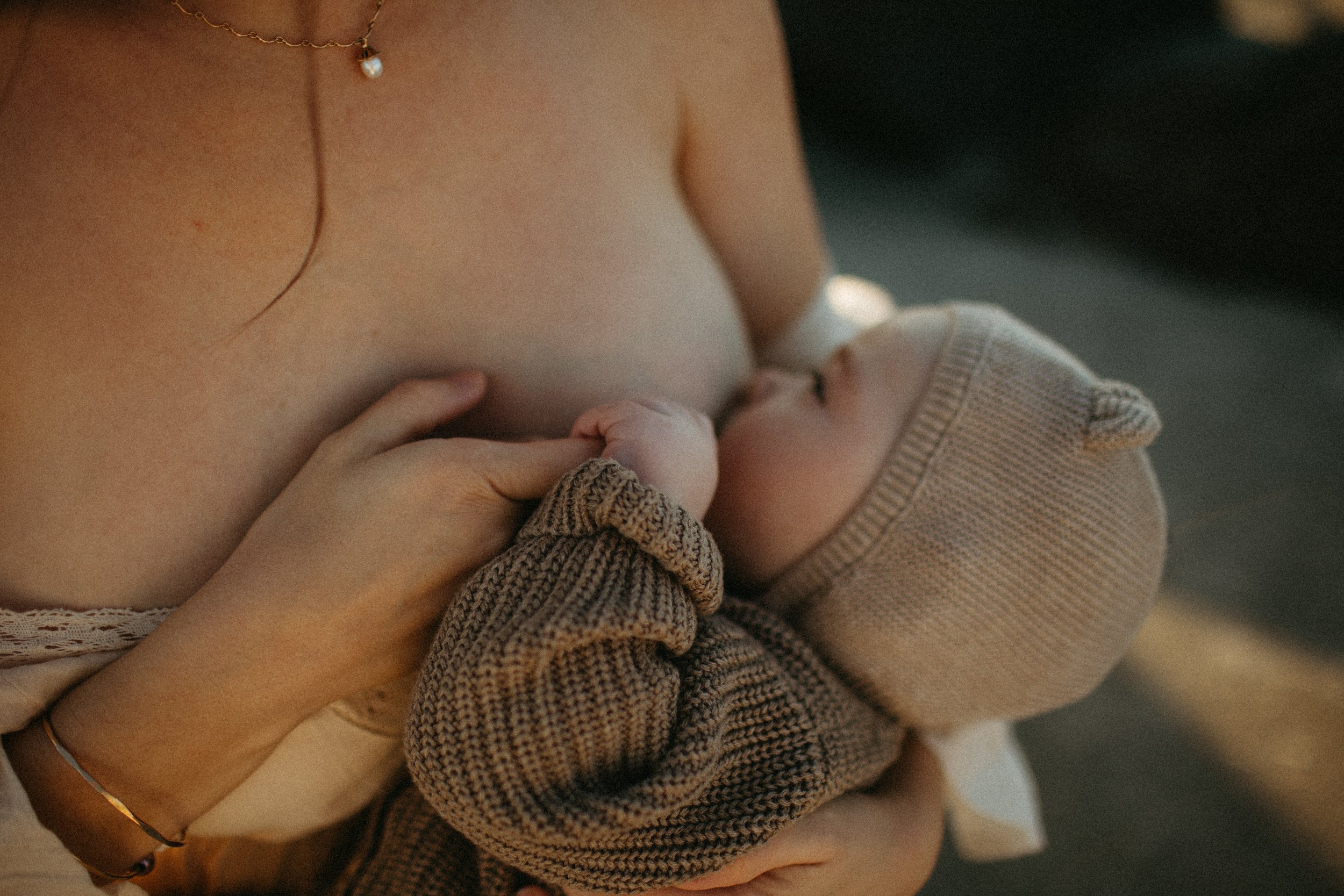 Mother breastfeeding baby wearing knitted outfit