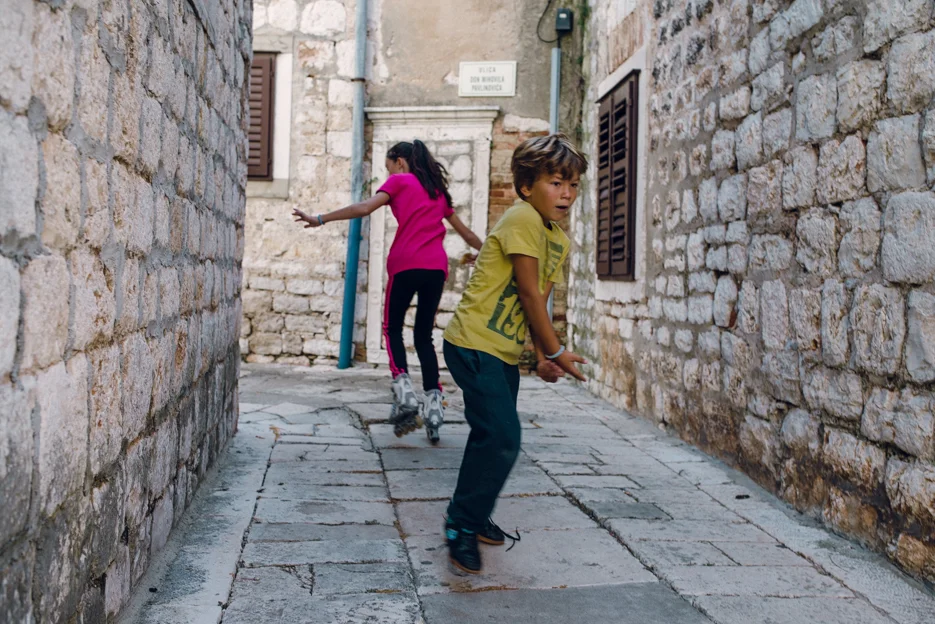 A girl roller blades on the uneven ground. The boy was having a "gun fight" with some of his friends - he was running with the girl but happened to do an about face right when I was snapping the photo.