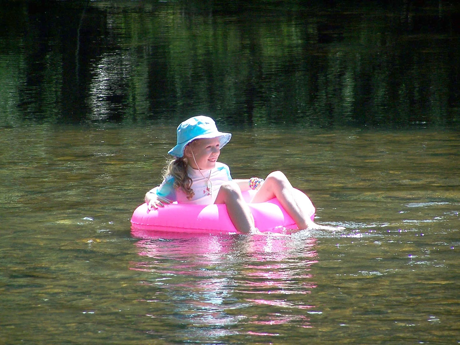 F. Lily In this photograph the broken reflection of my daughter Lily and her pink float are shown in the river. It can be clearly seen how the reflection alternates between showing the pink float and the trees at the side of the river.