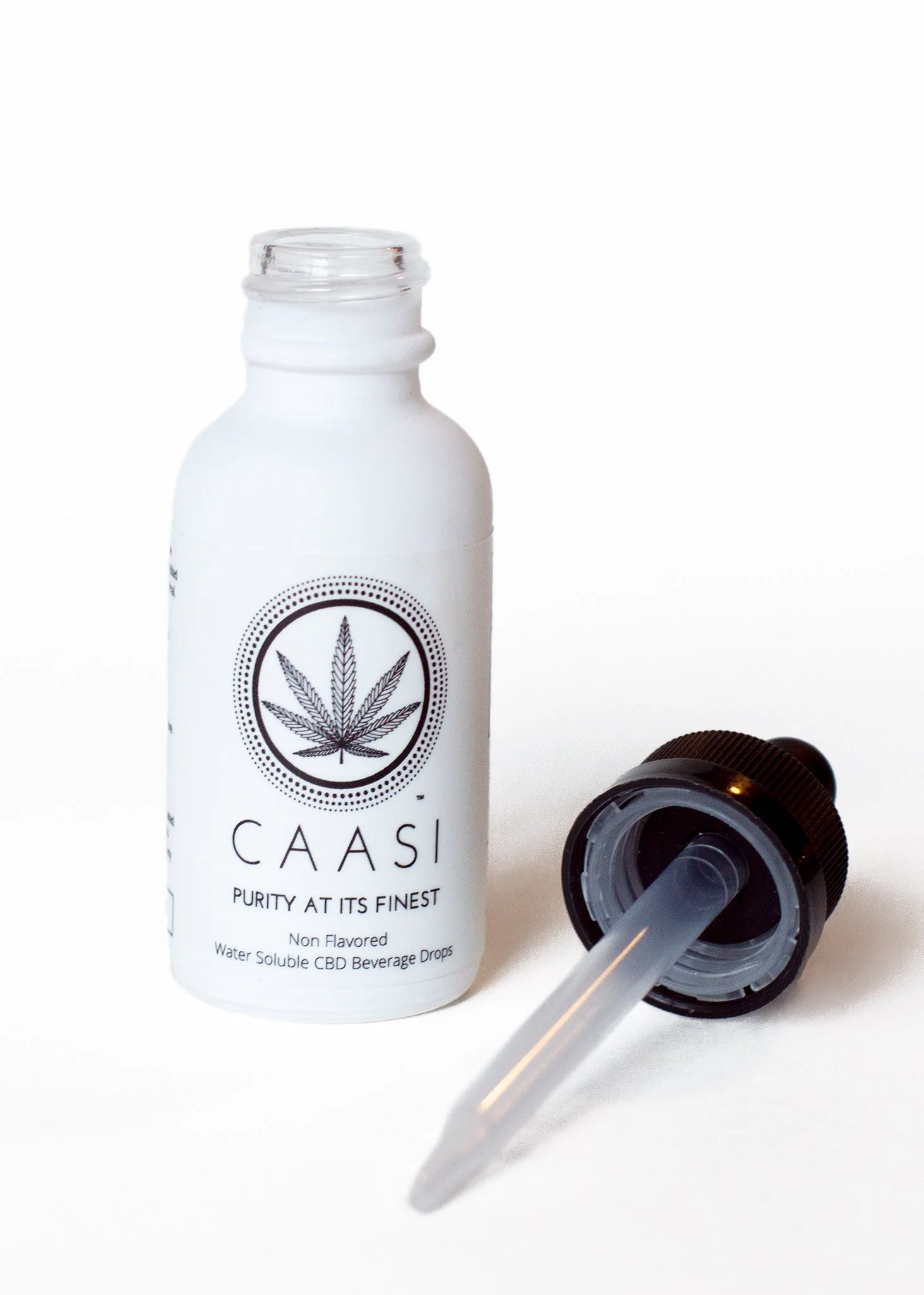 A white bottle labeled 'CAASI' with a cannabis leaf logo and a dropper lying next to it on a white background.