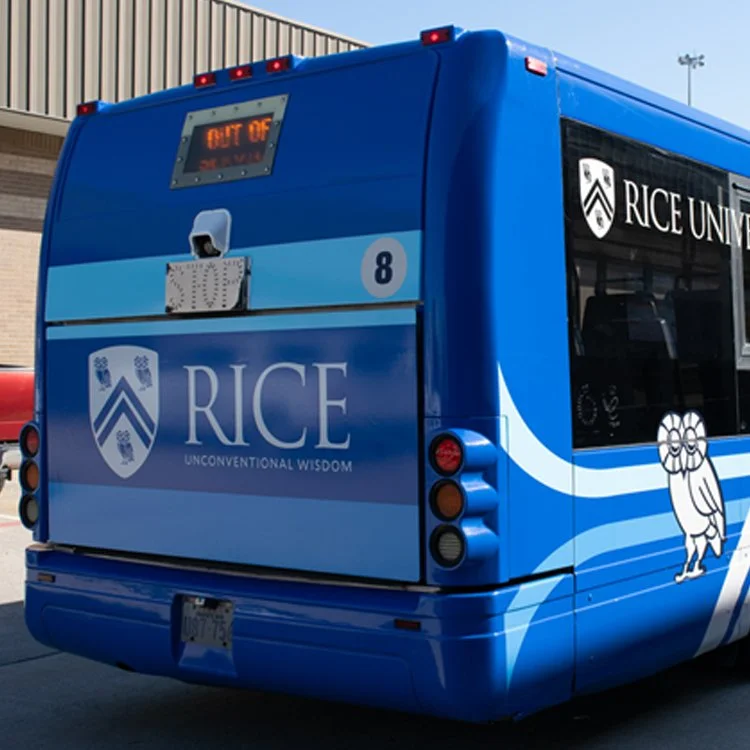 Rice University bus featuring a blue fleet wrap with university branding, logo graphics, and the Rice owl mascot.