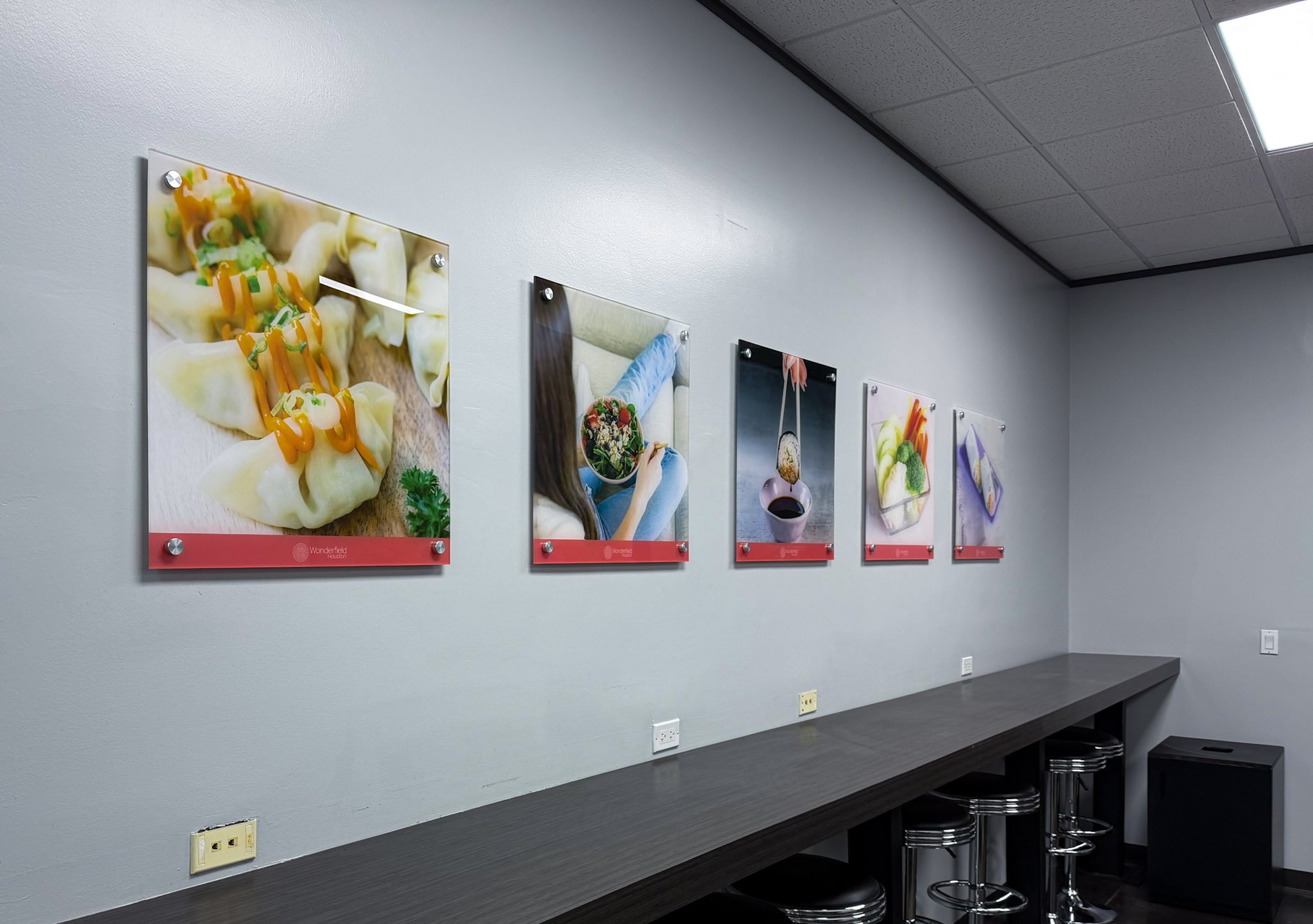 Acrylic prints with food imagery mounted on standoffs along an office break room wall.
