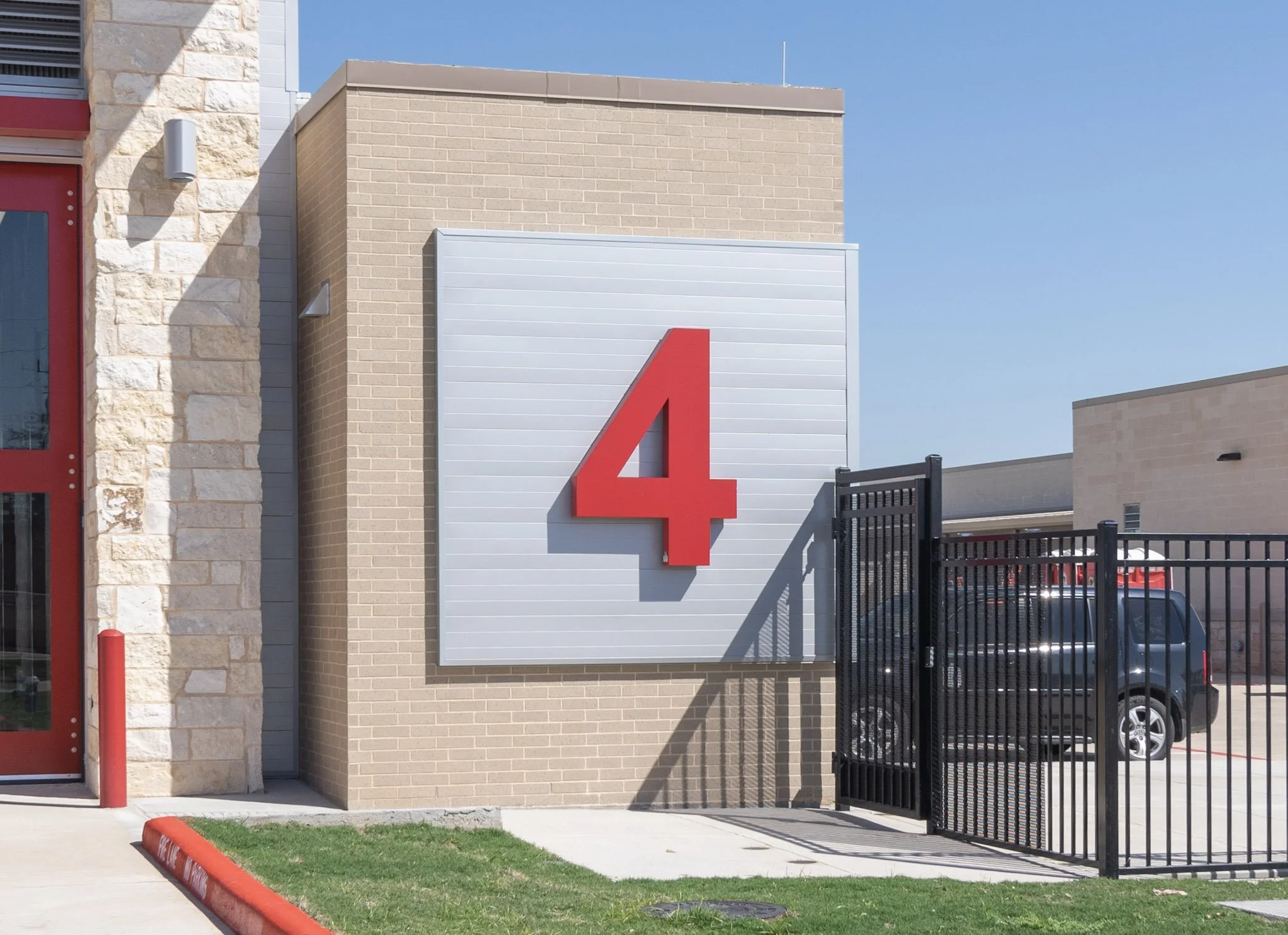 Non-illuminated red channel letter building number 4 mounted on an ACM backer panel at a fire station in Houston.