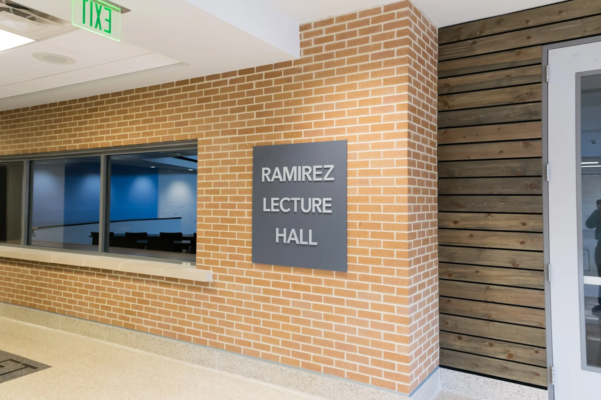 Dimensional aluminum letters mounted on a gray panel identifying Ramirez Lecture Hall inside an educational facility.