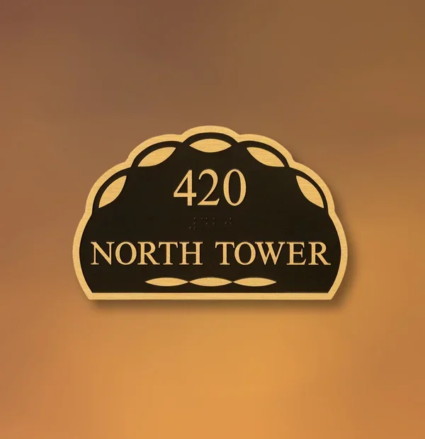 Decorative ADA building location sign in Houston reading “420 North Tower” with raised lettering on a black plaque framed by a sculpted gold edge.