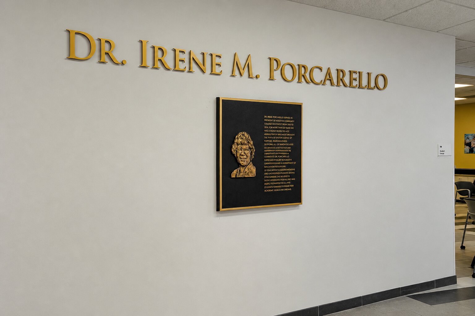 Bronze recognition plaque and dimensional lettering honoring Dr. Irene M. Porcarello installed on an interior HCC wall.
