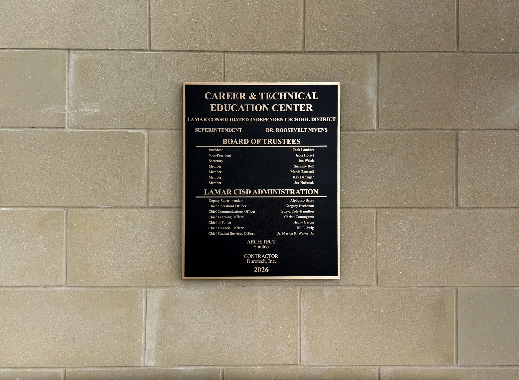 Custom building plaque for the Lamar CISD Career & Technical Education Center mounted on an interior concrete block wall.