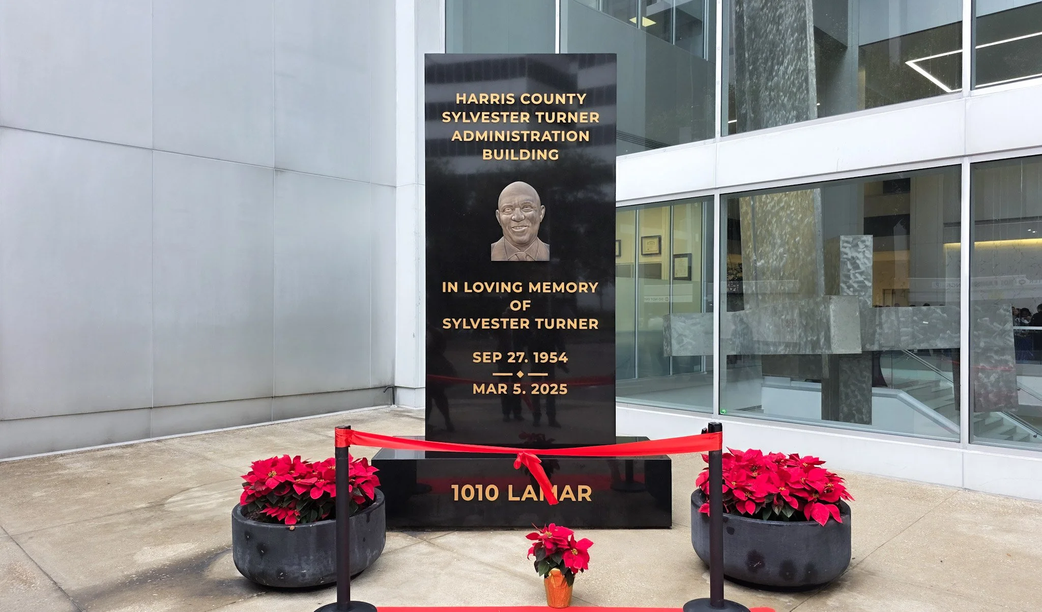 Black monument plaque at Harris County building in Houston honoring Sylvester Turner with engraved gold lettering and portrait.