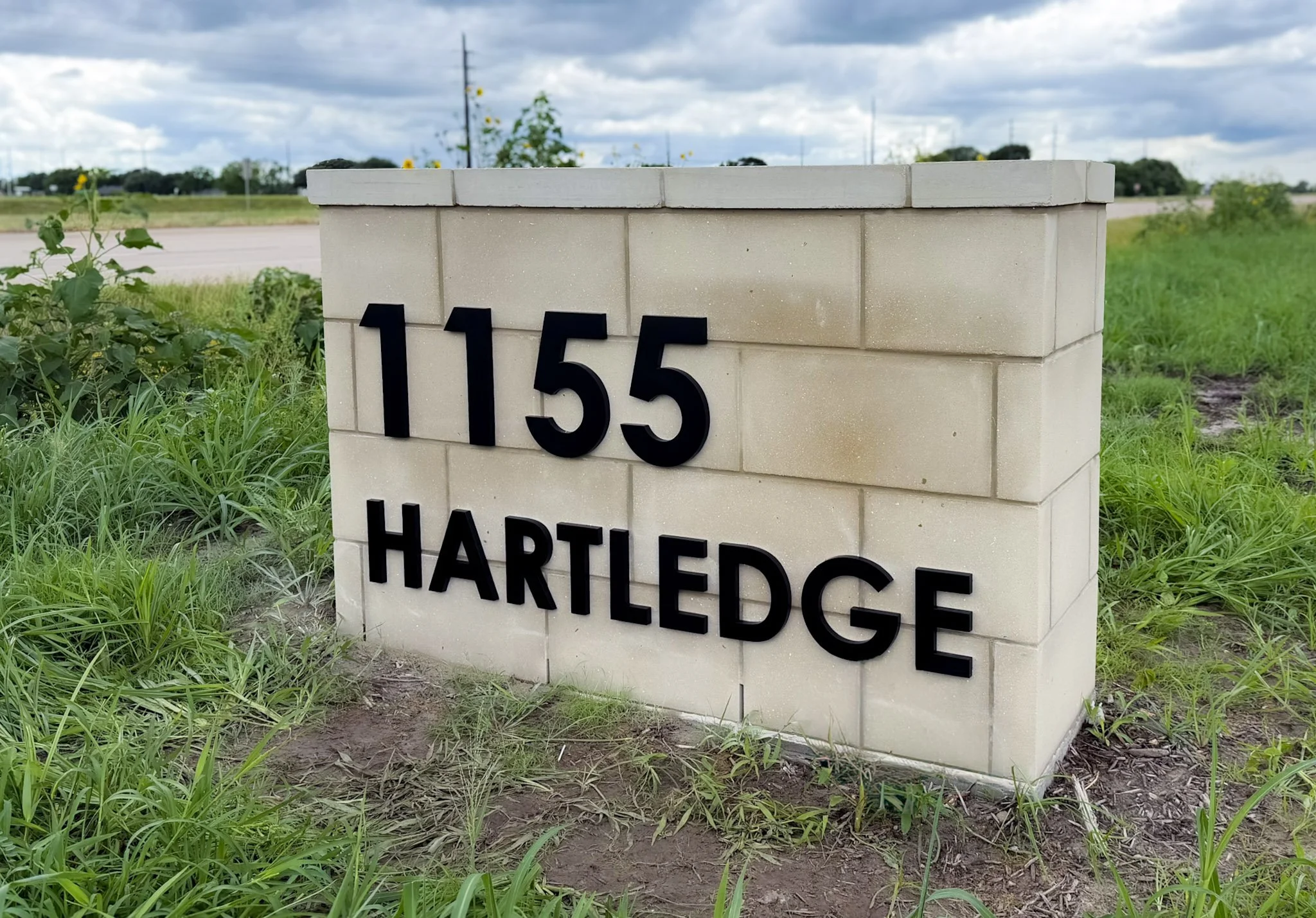 Masonry monument sign with dimensional address numbers and lettering installed at the Hartledge community entrance for neighborhood identification.