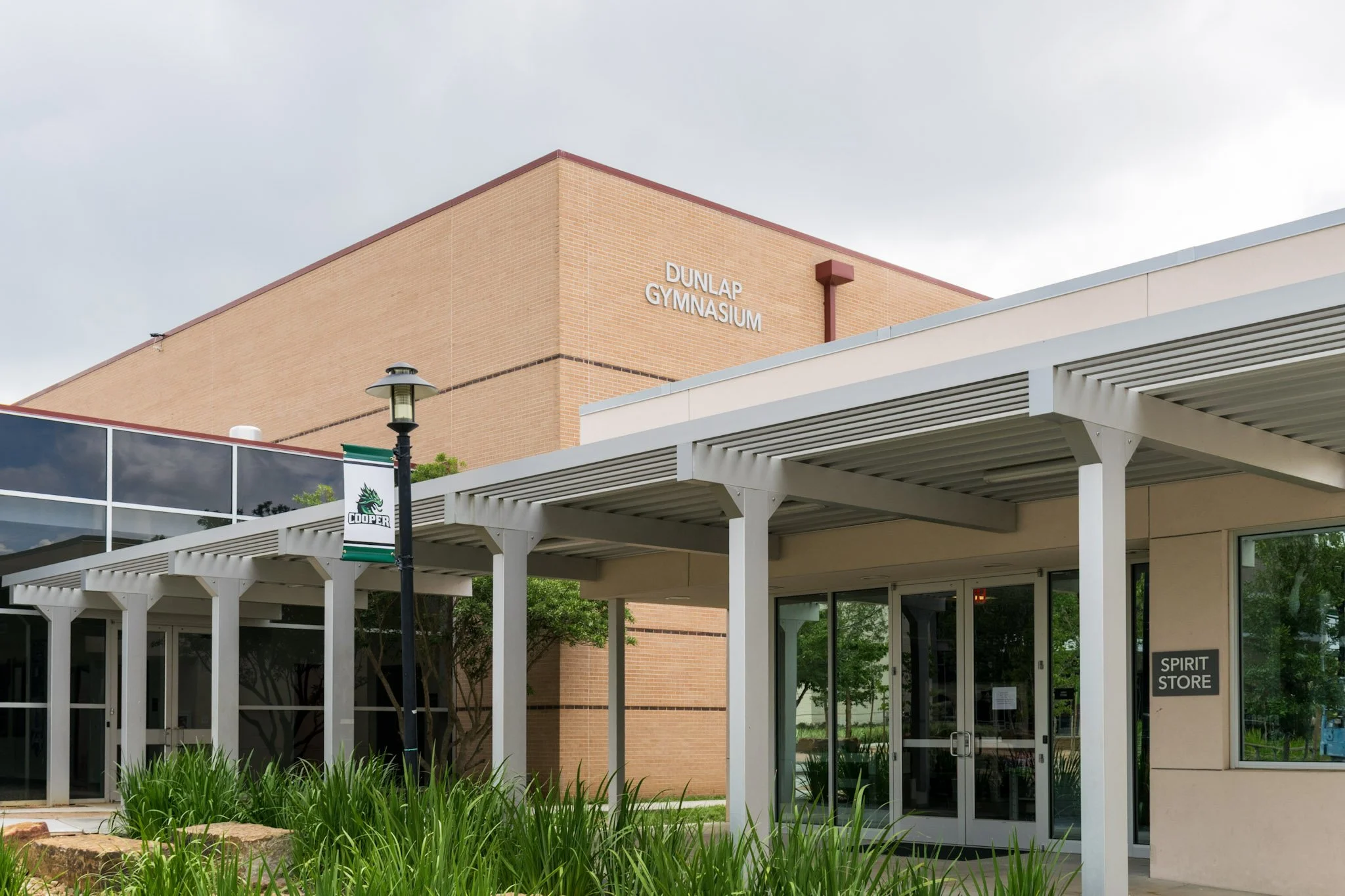 Exterior building sign with dimensional letters identifying Dunlap Gymnasium at The John Cooper School entrance in The Woodlands, Texas.