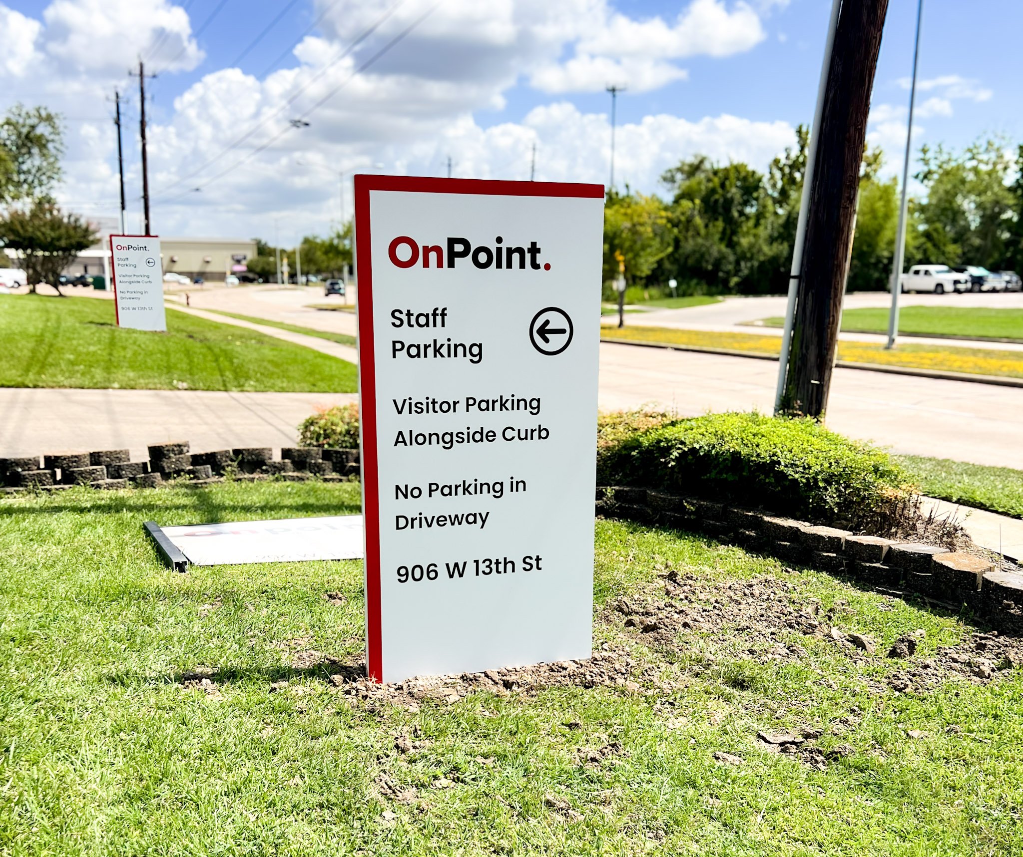 Freestanding directional wayfinding sign for OnPoint showing staff parking, visitor parking, and driveway directions outside a commercial property in Houston, Texas.
