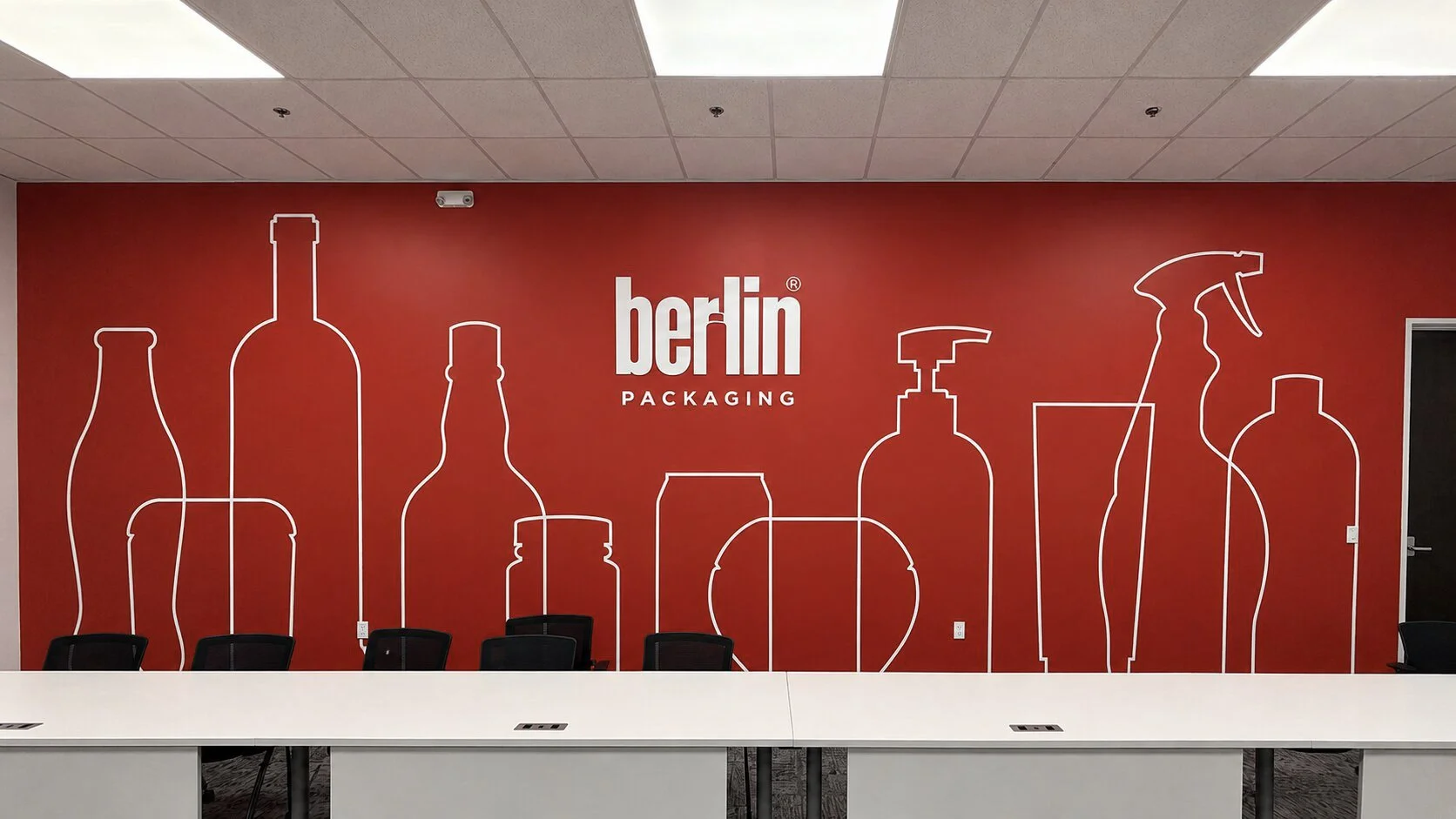 Berlin Packaging branded wall wrap featuring white bottle outline graphics on a red background.