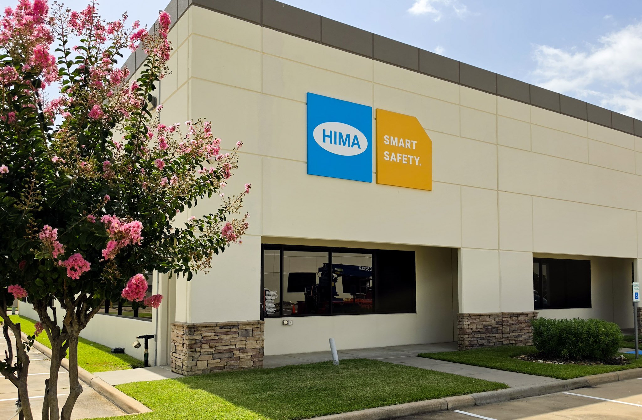 Exterior HIMA building sign with custom branded panels mounted on a commercial office building in Houston, Texas.