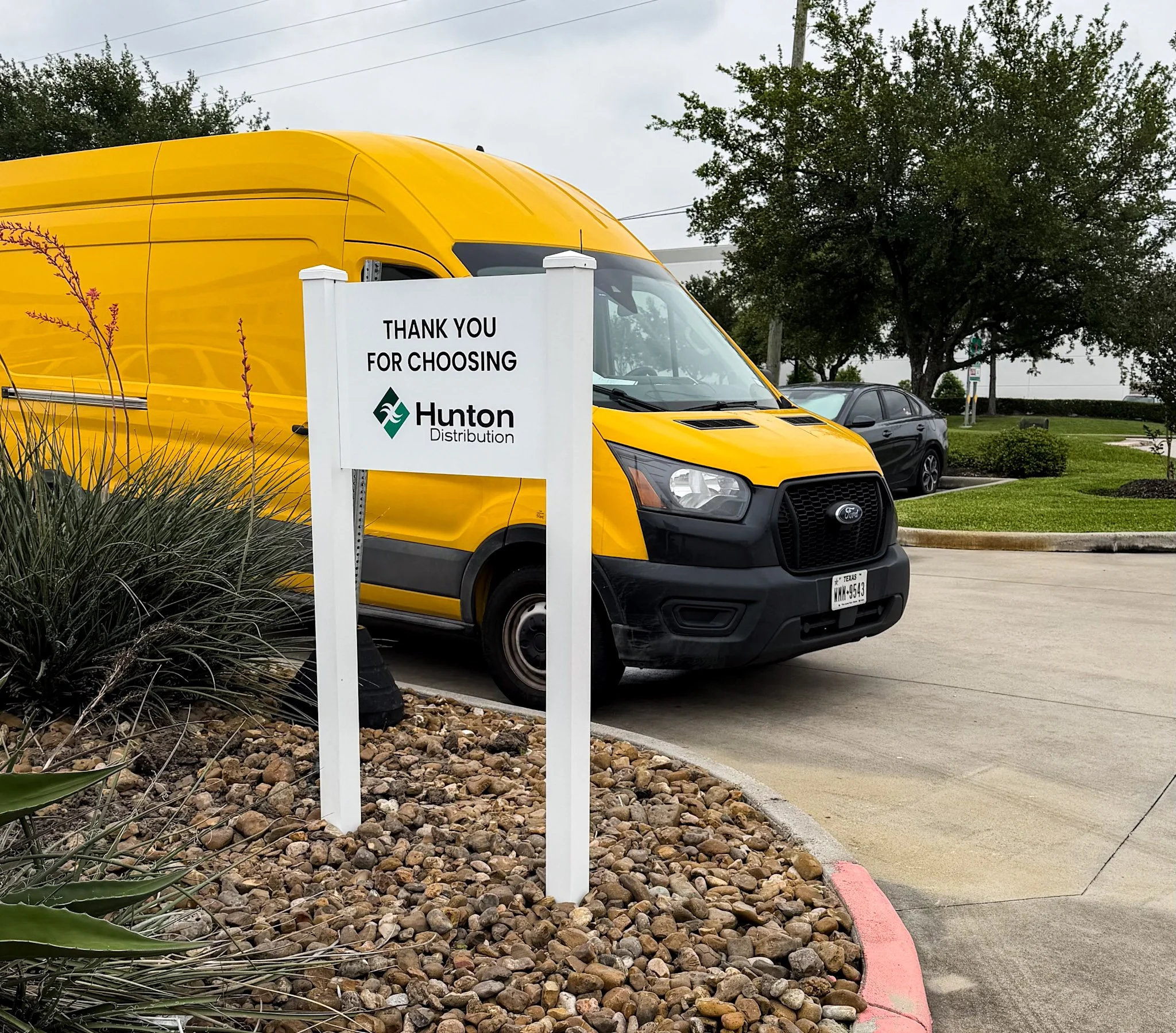 Custom post and panel sign for Hunton Distribution installed at a commercial property entrance in Houston, Texas.