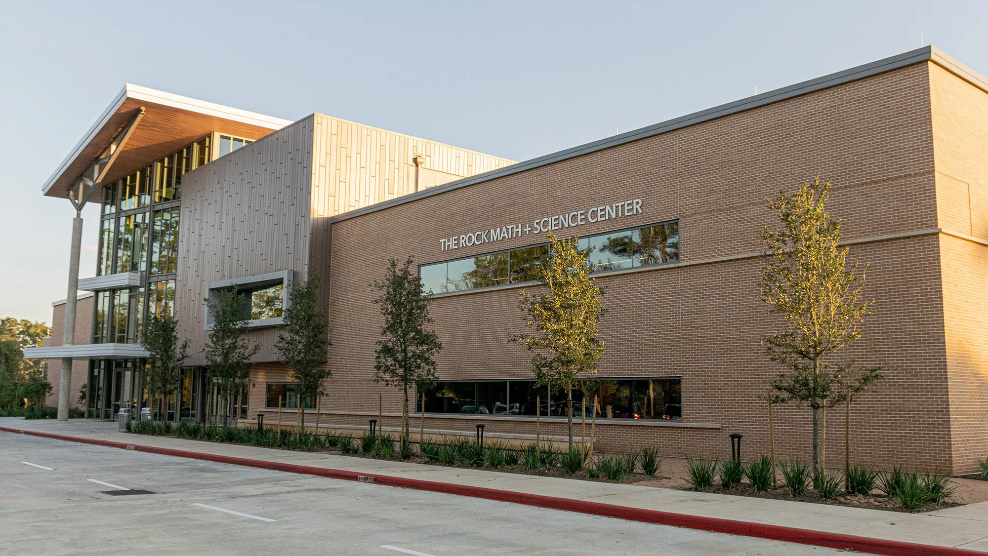Dimensional exterior signage reading “THE ROCK MATH + SCIENCE CENTER” mounted on a modern brick school building facade in Houston.